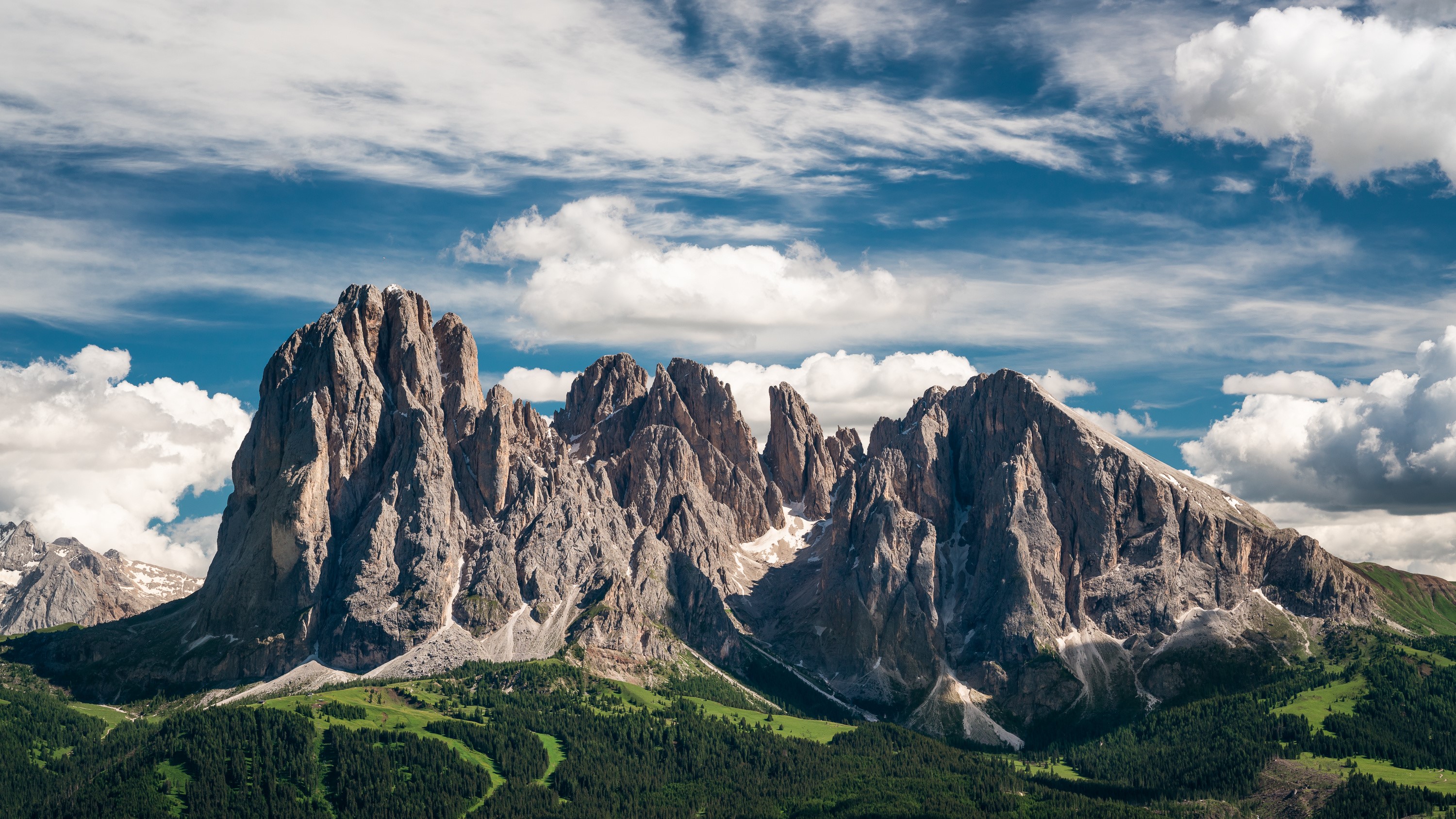 Jagged mountain peaks under a cloudy blue sky HD Wallpaper
