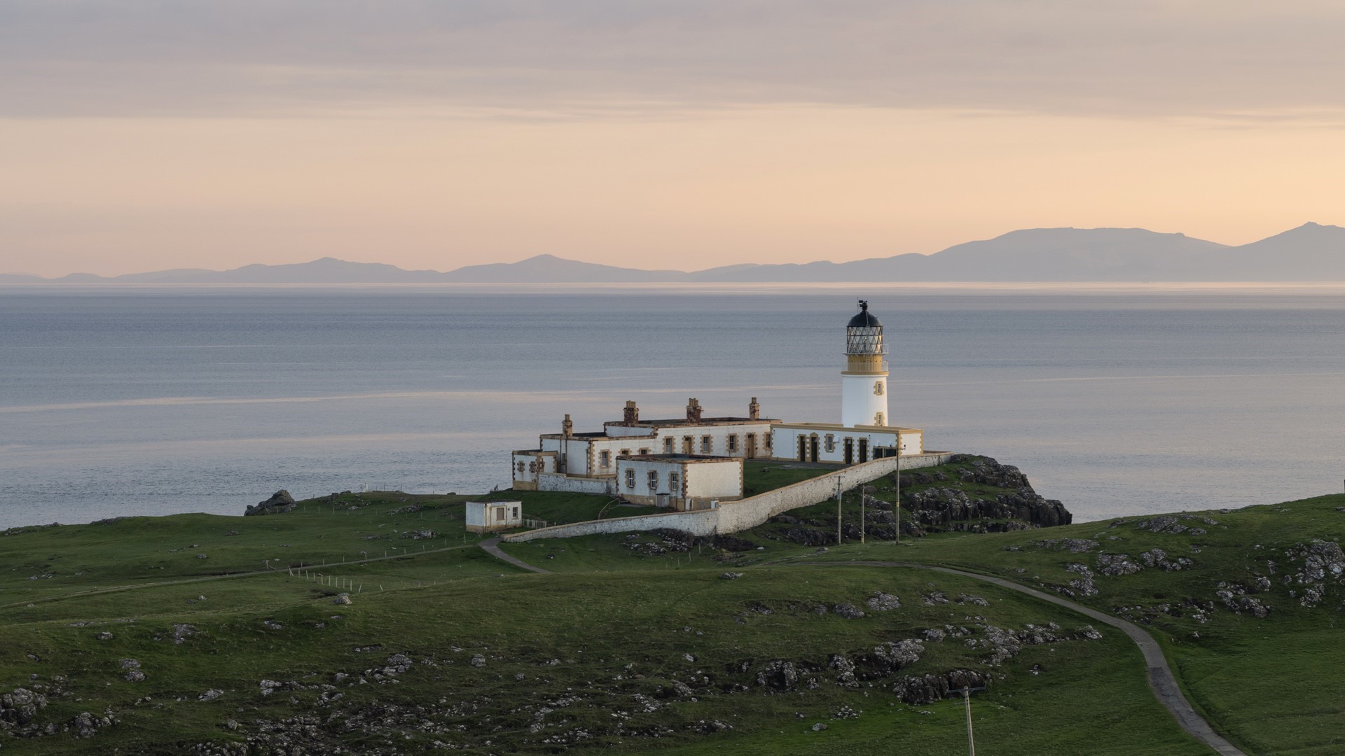 Lighthouse on a rocky coast overlooking the sea HD Wallpaper