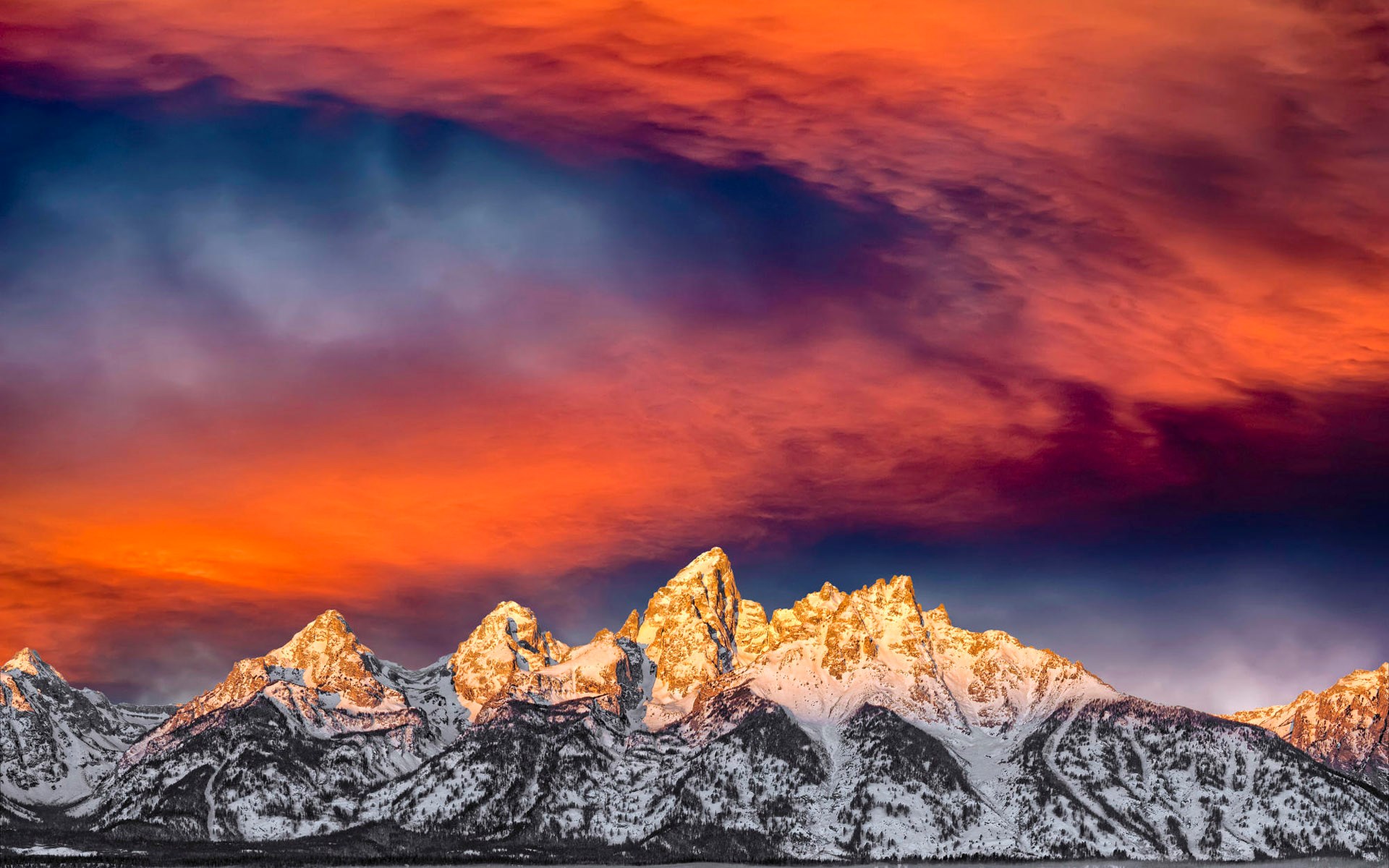 Snow-covered mountains under a fiery sunset sky HD Wallpaper