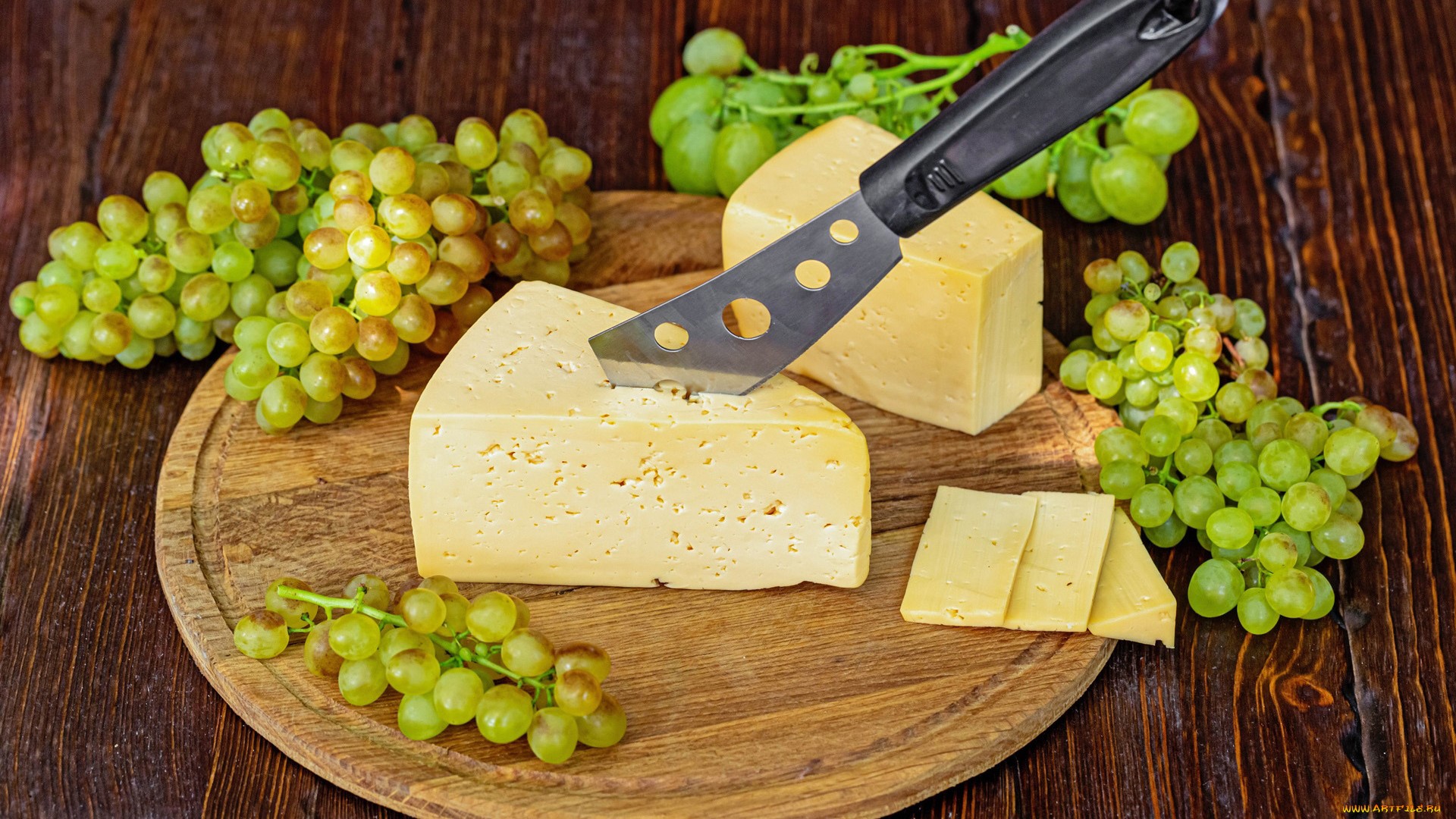 Cheese and grapes on a wooden board with a knife HD Wallpaper