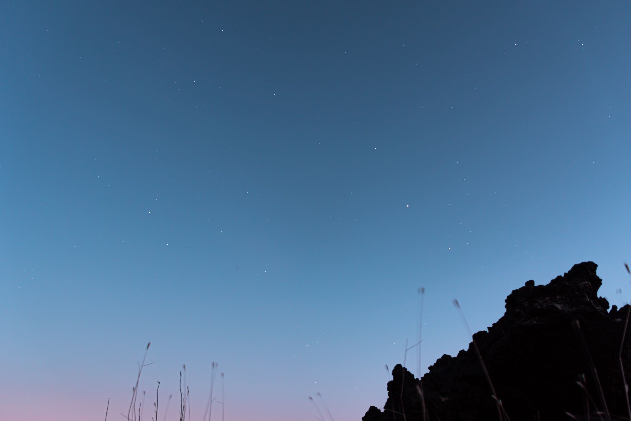 Night sky with stars over rocky landscape and grass HD Wallpaper