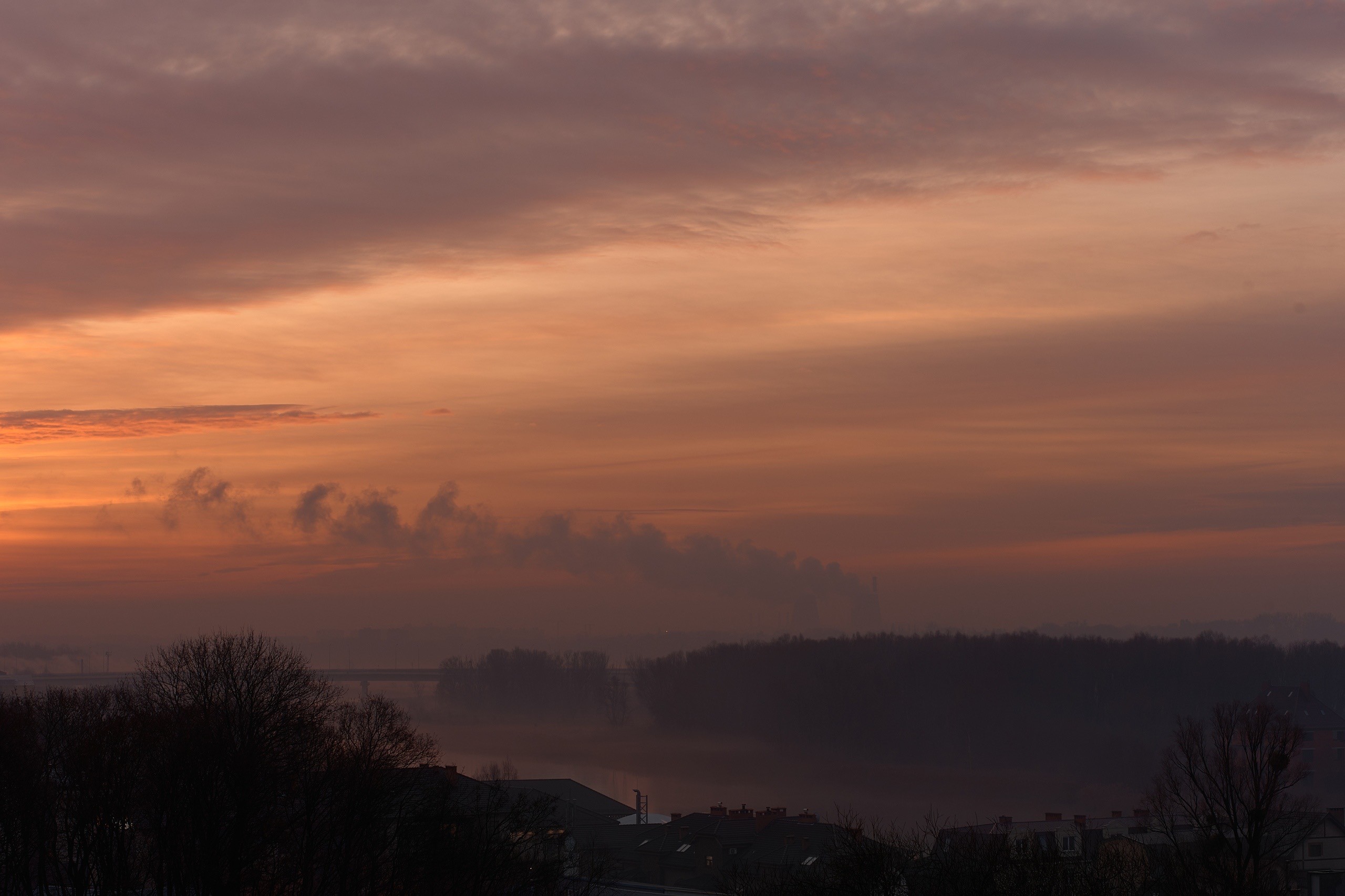 Sunrise over a misty landscape with trees and buildings HD Wallpaper