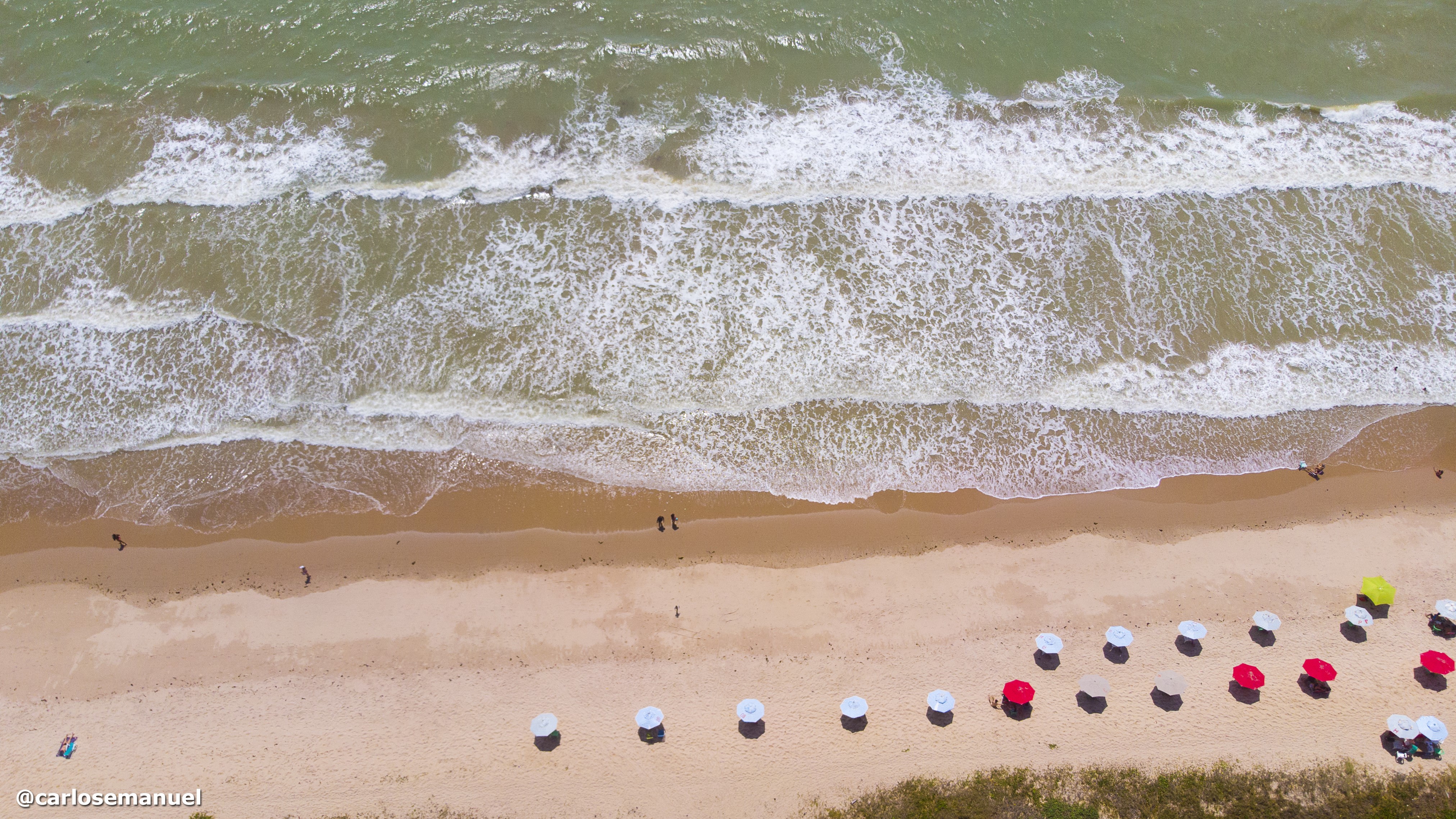 Aerial view of a beach with colorful umbrellas and waves HD Wallpaper