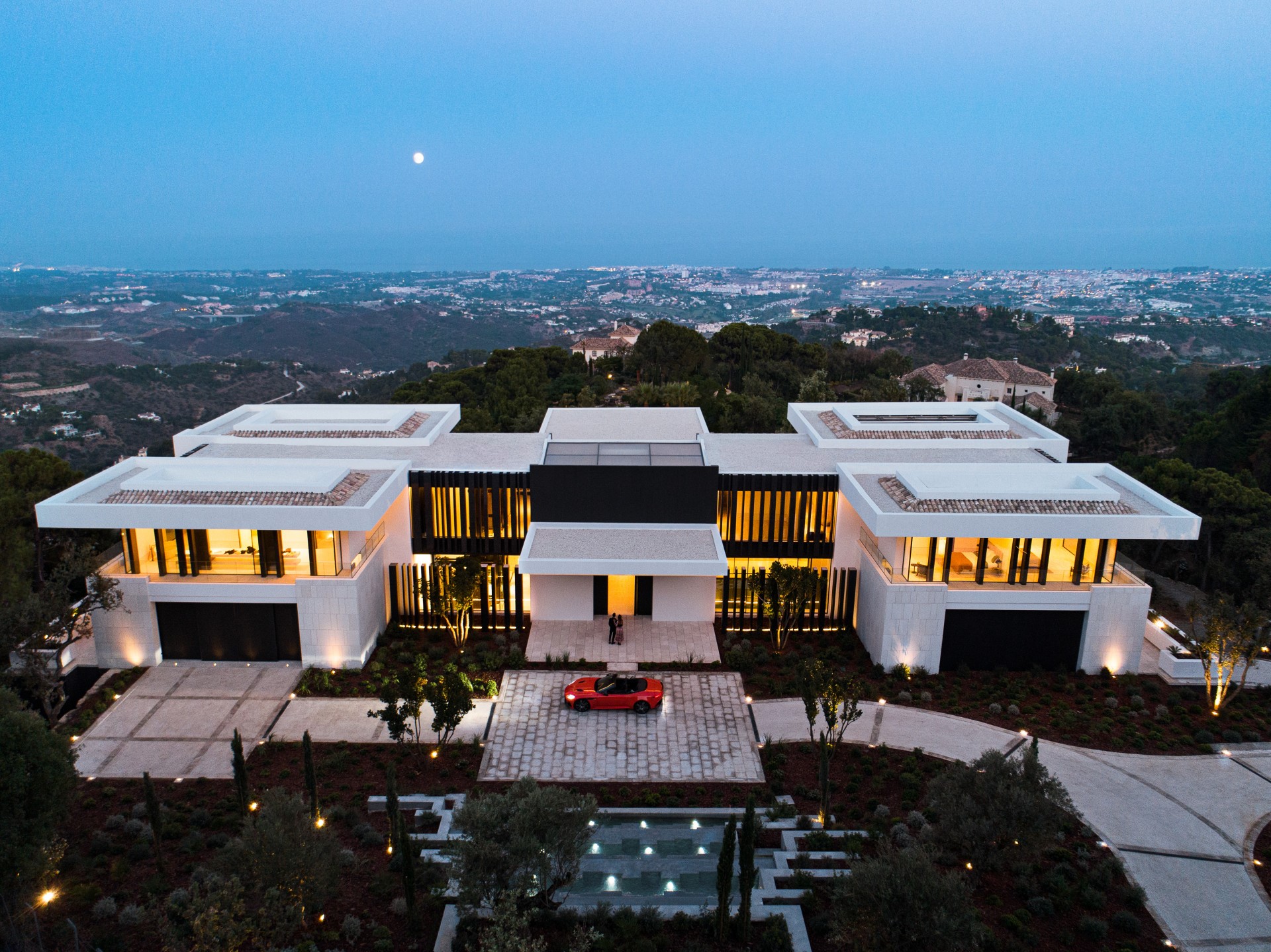 Modern mansion with a red car at dusk HD Wallpaper
