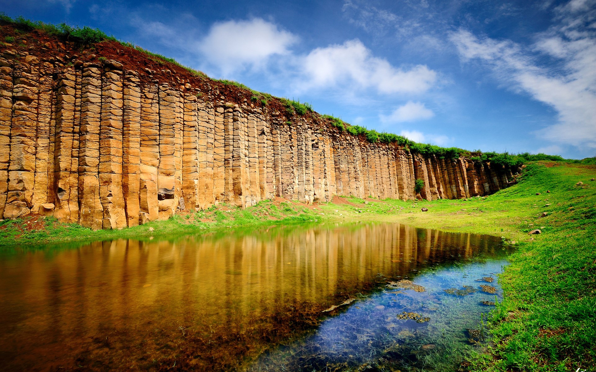 Columnar basalt cliff formation reflected in water HD Wallpaper