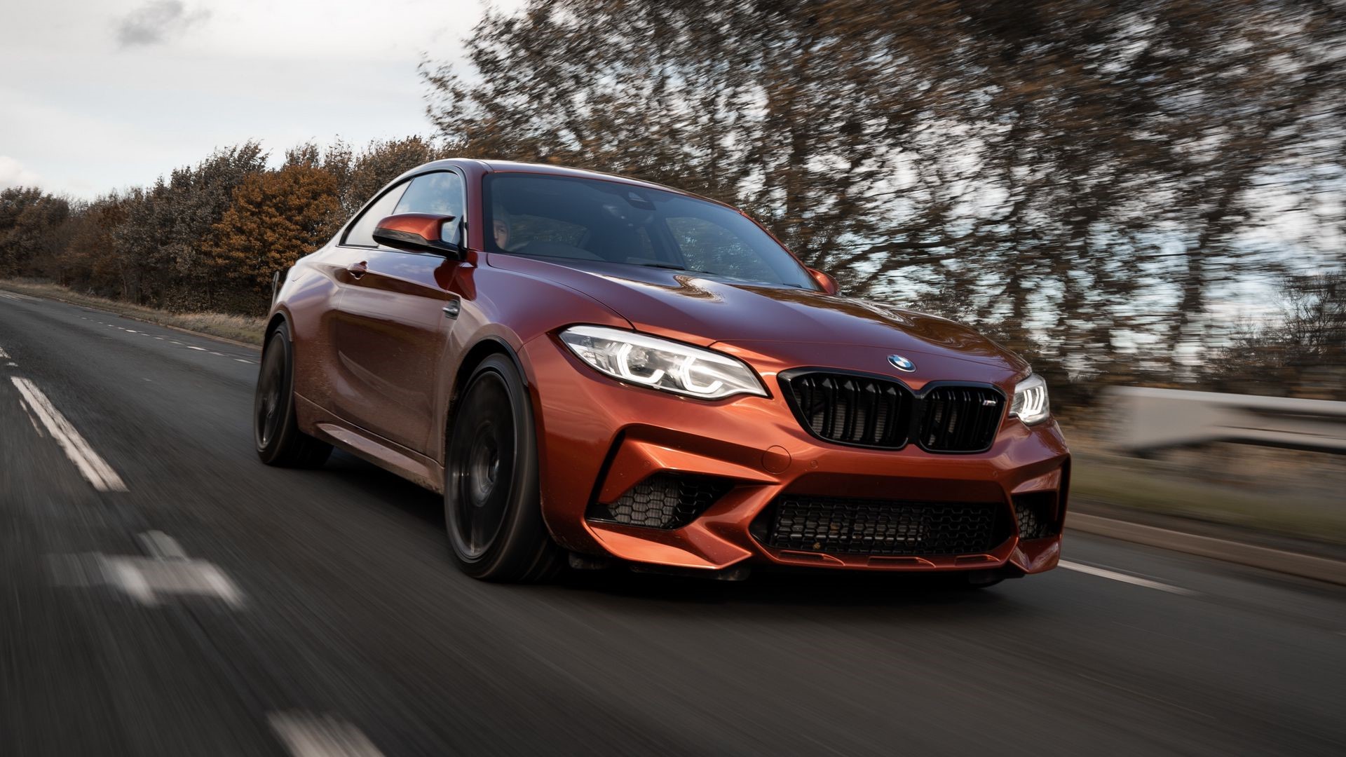Orange BMW M2 driving on a road with motion blur HD Wallpaper