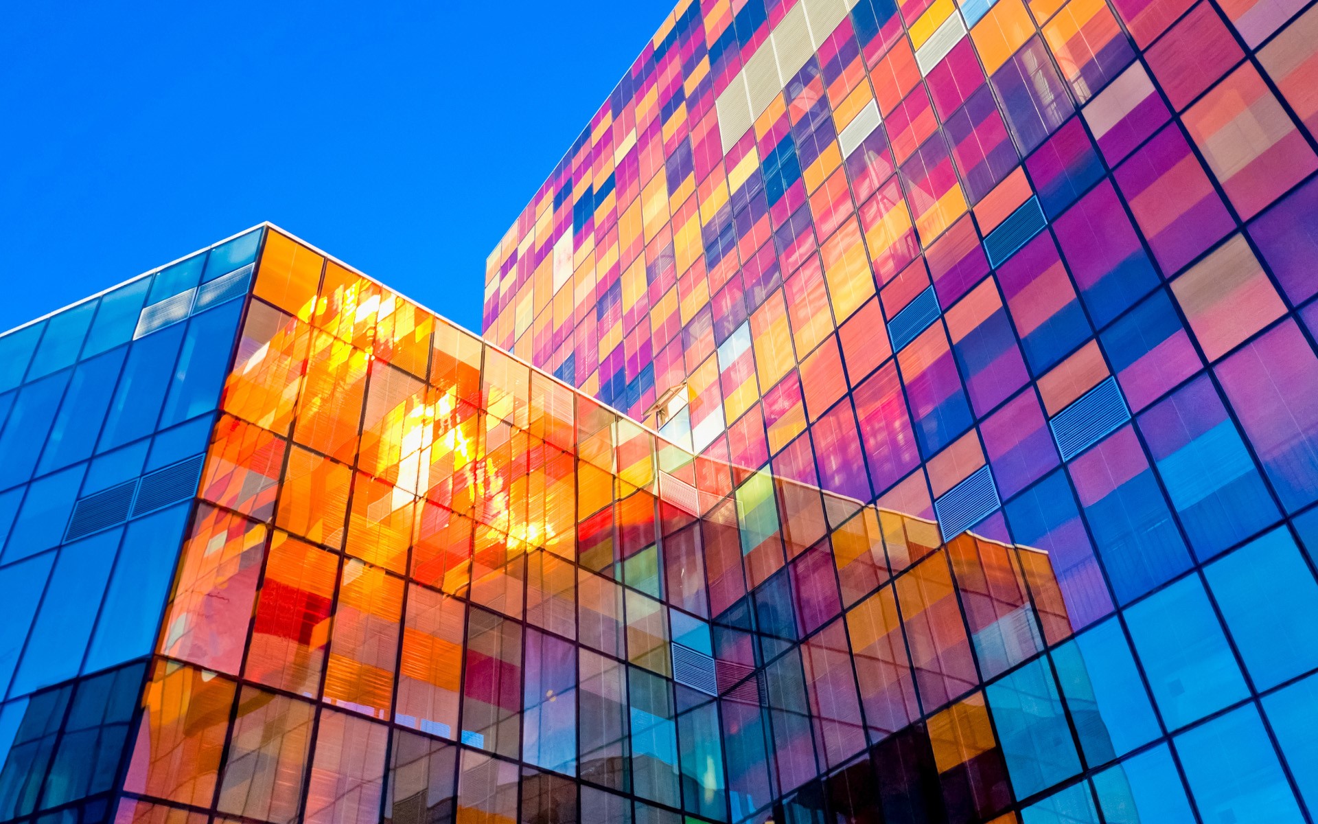 Modern building with colorful glass facade under blue sky HD Wallpaper