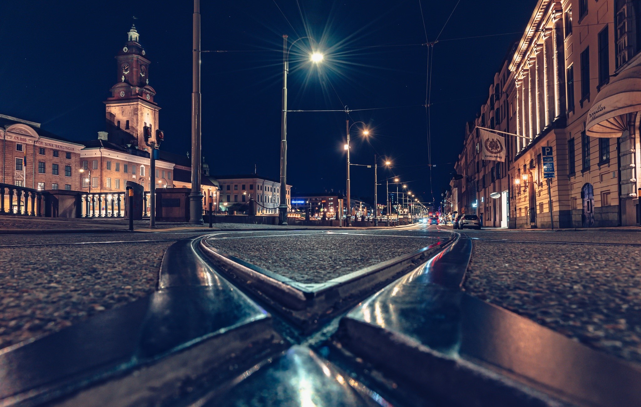 City street at night with tram tracks in the foreground HD Wallpaper