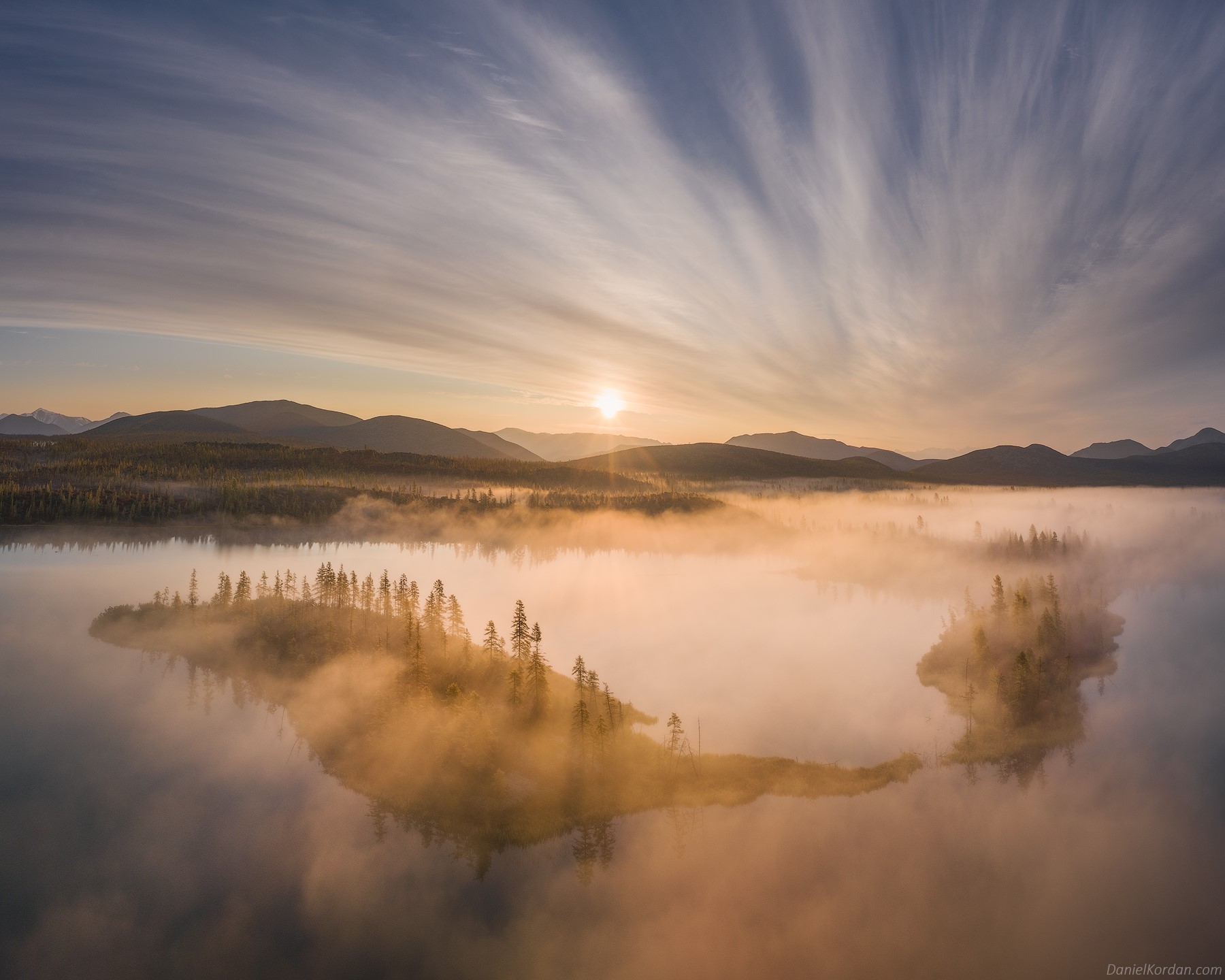 Island in a misty lake at sunrise with mountains and clouds HD Wallpaper