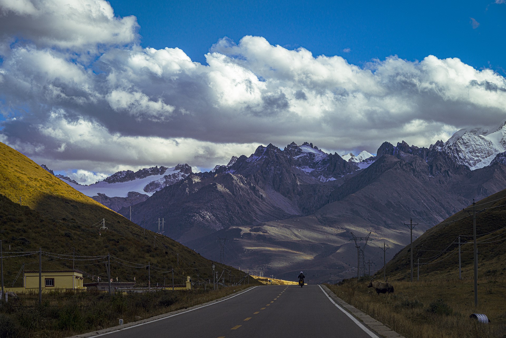 Motorcyclist on a mountain road under clouds HD Wallpaper