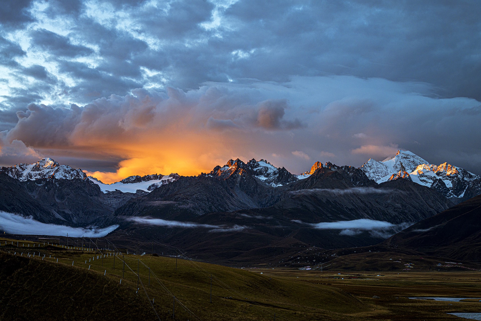 Sunset over snow-capped mountains with dramatic clouds HD Wallpaper