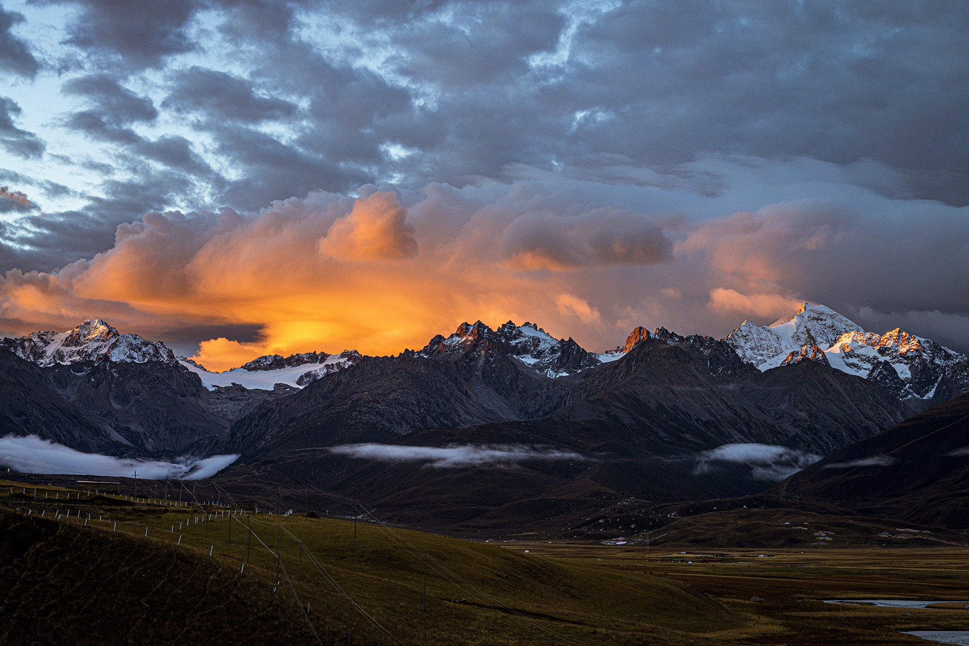Sunset over snow-capped mountains with dramatic clouds HD Wallpaper