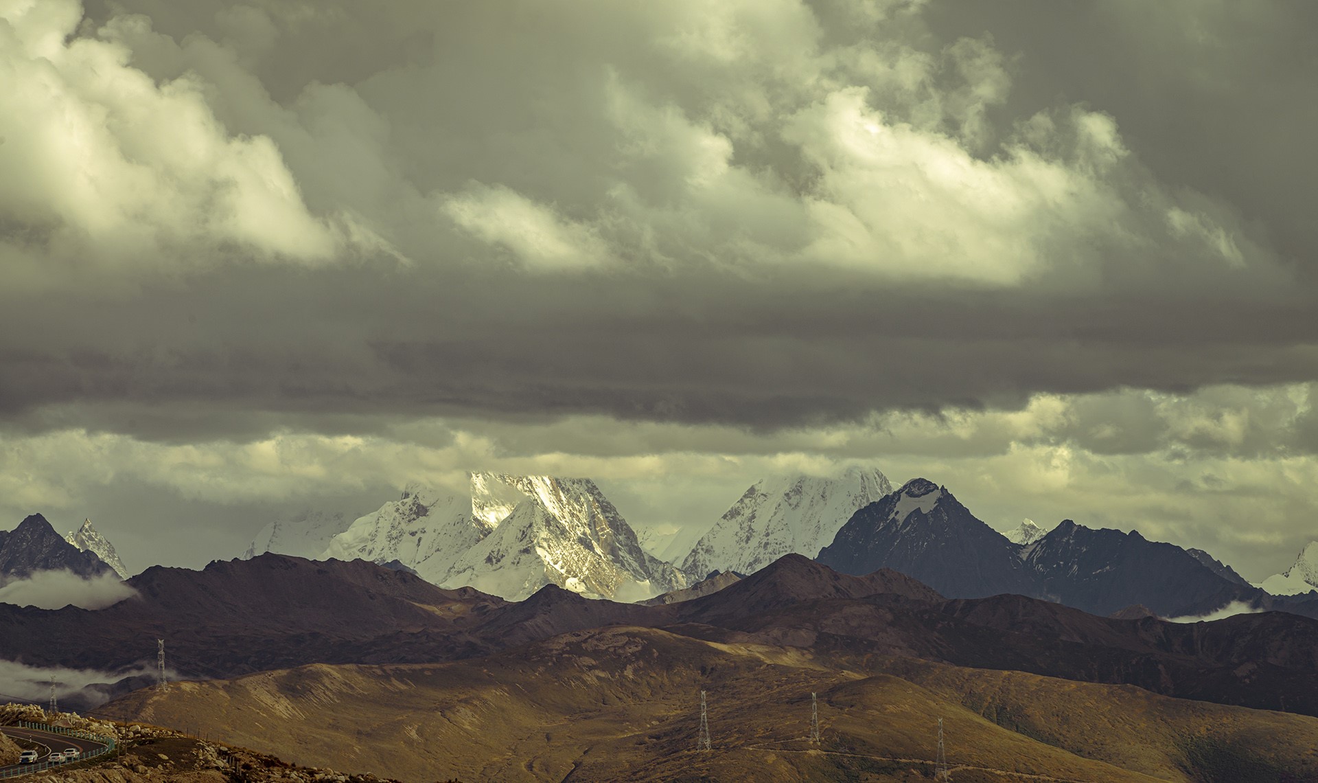 Snow-capped mountains under dramatic clouds HD Wallpaper