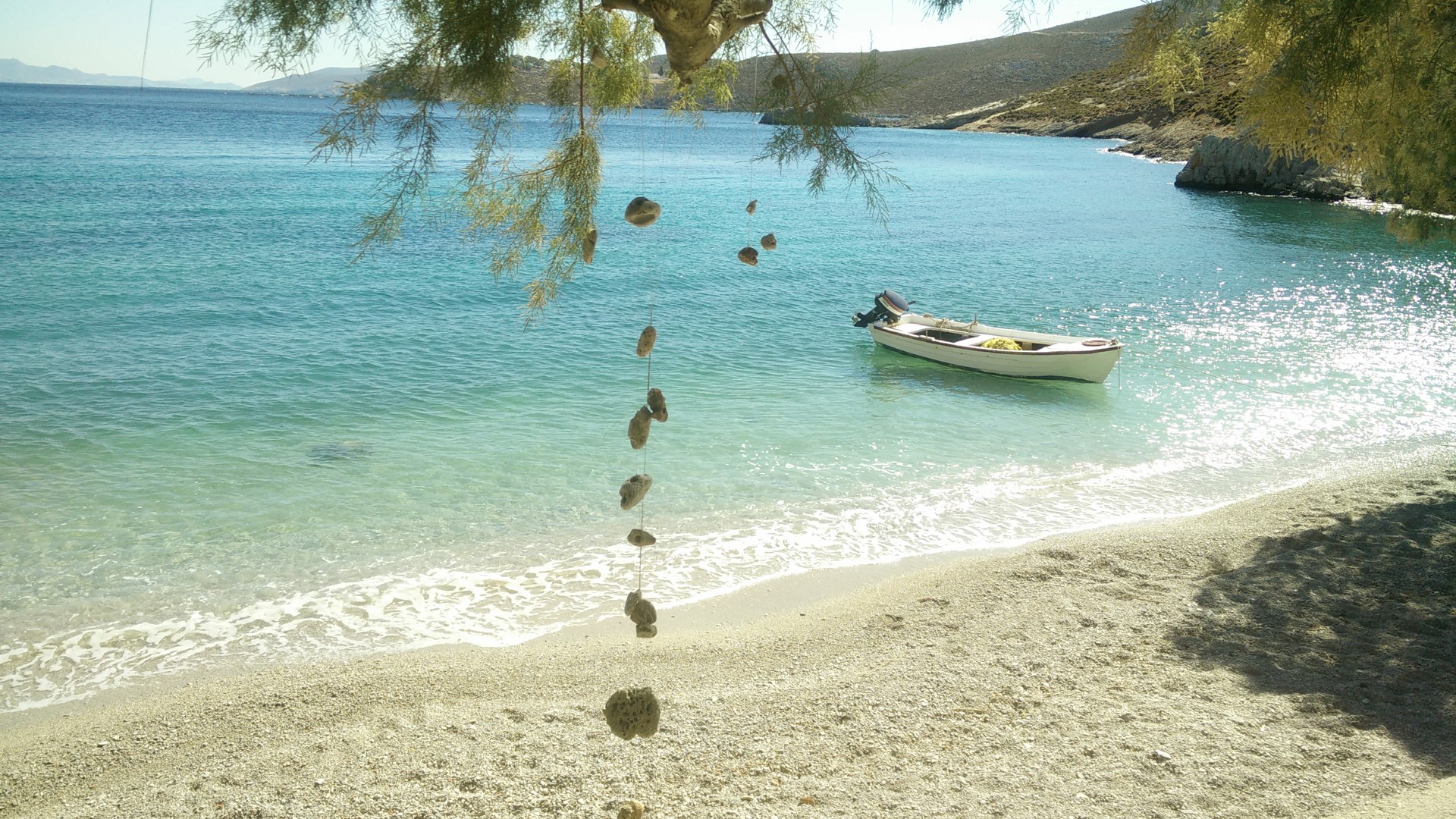 Boat anchored in a clear turquoise bay on Kalymnos, Greece HD Wallpaper