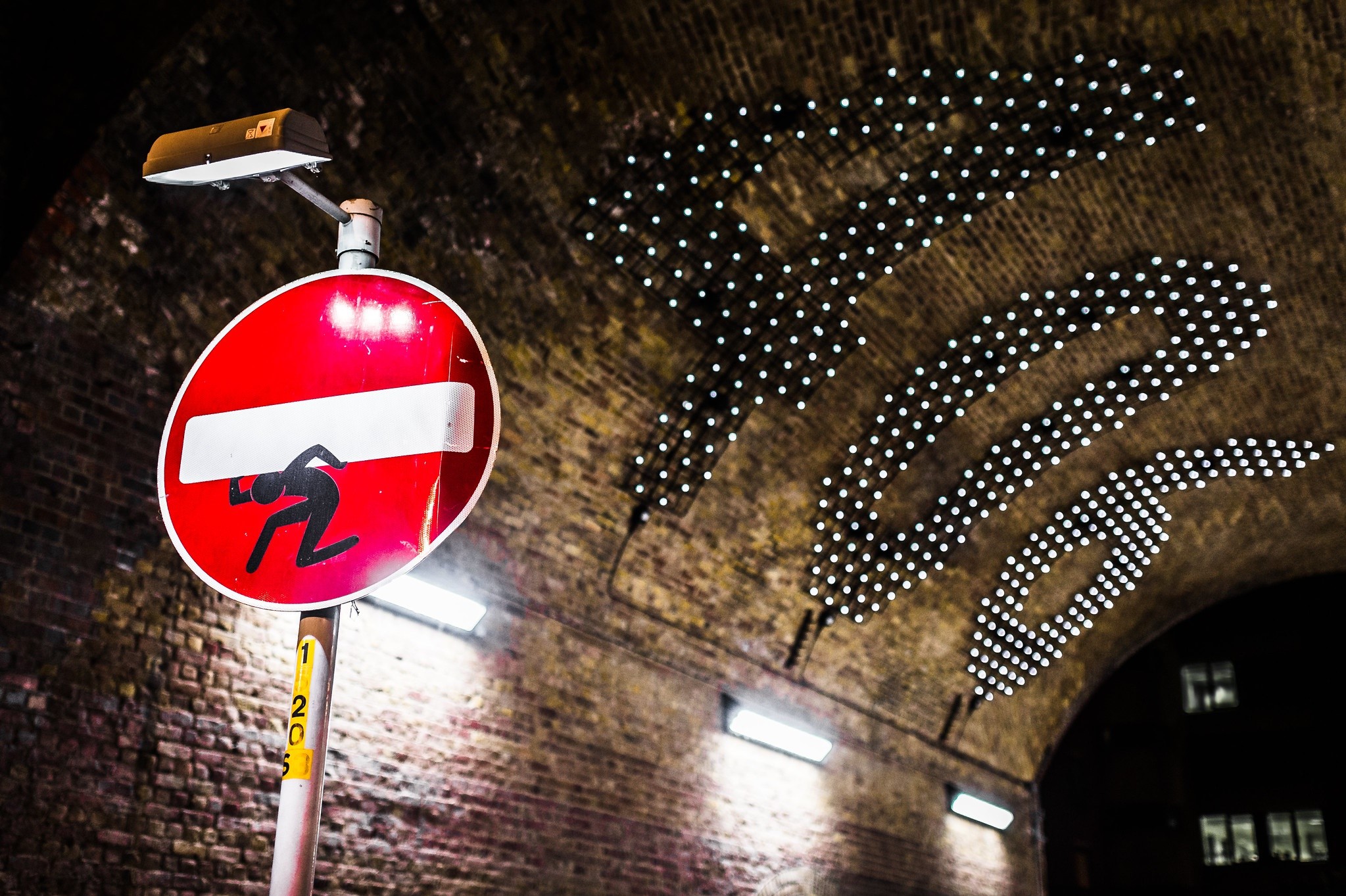 Street sign with figure under brick archway in London HD Wallpaper