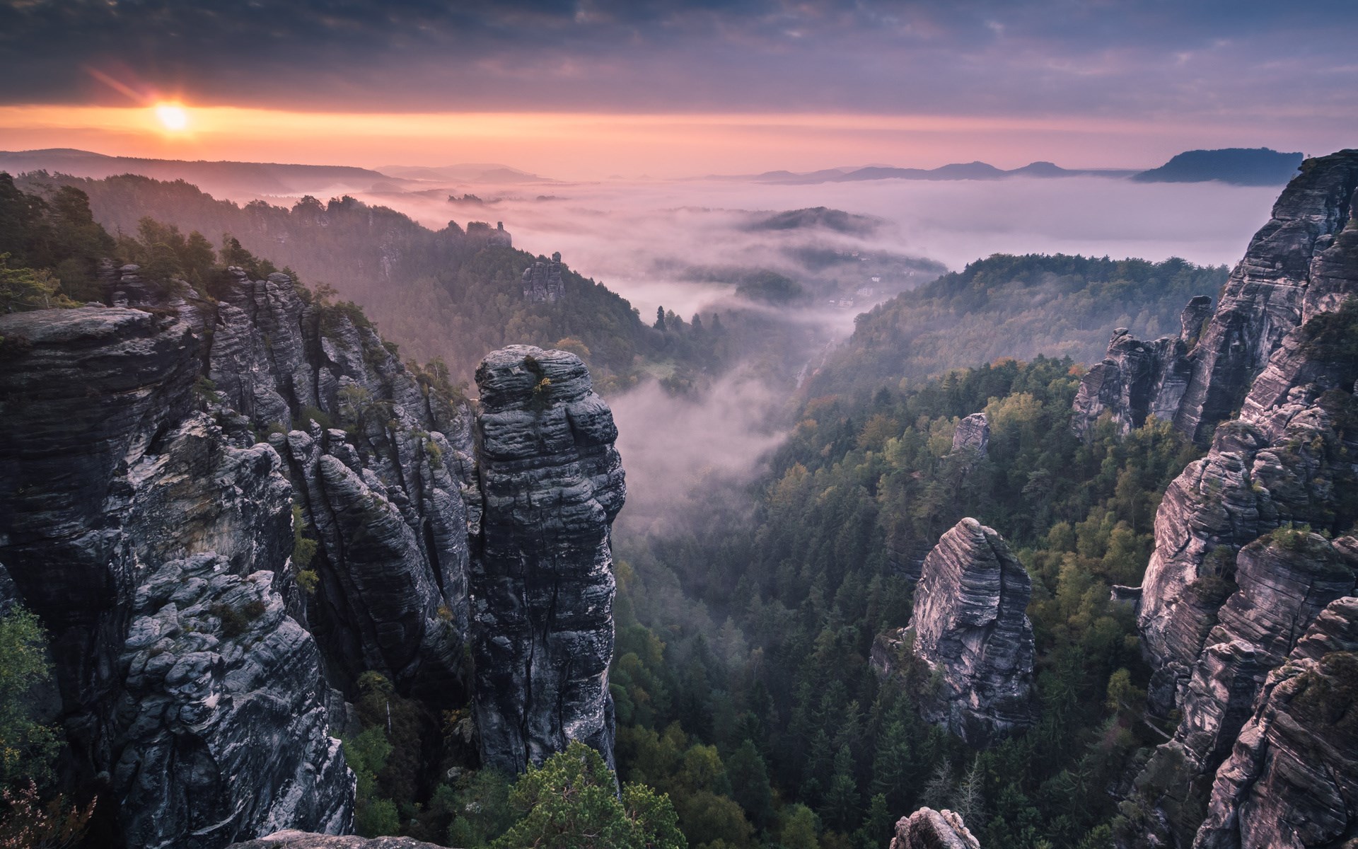 Misty mountain valley at sunrise with rock formations HD Wallpaper