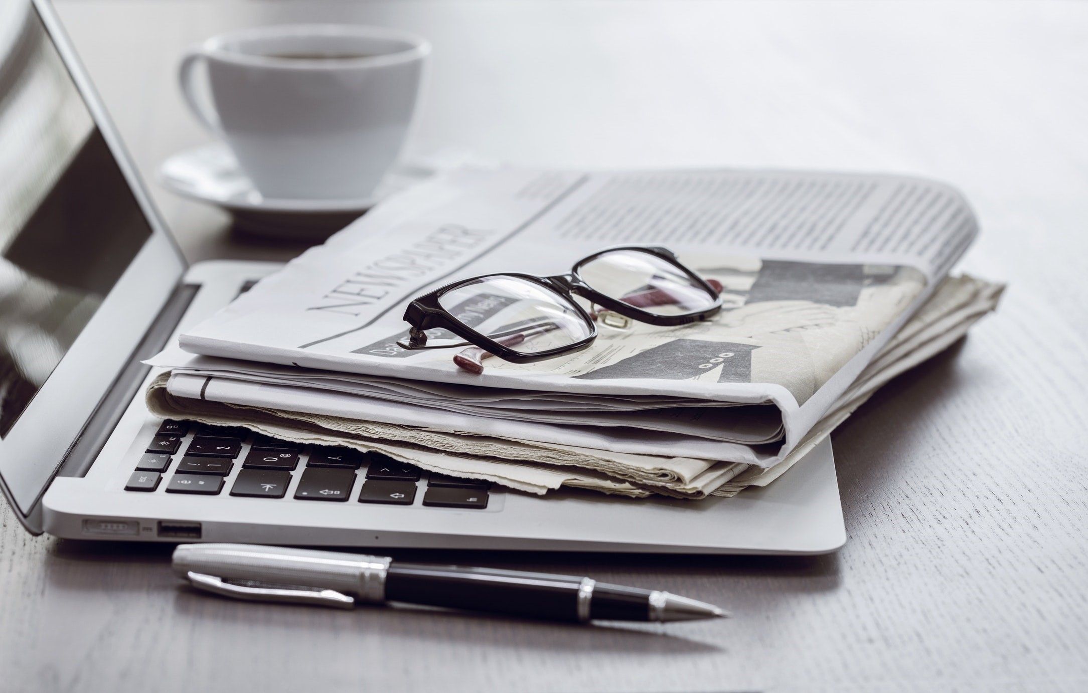 Laptop with newspapers, glasses, pen, and coffee cup HD Wallpaper