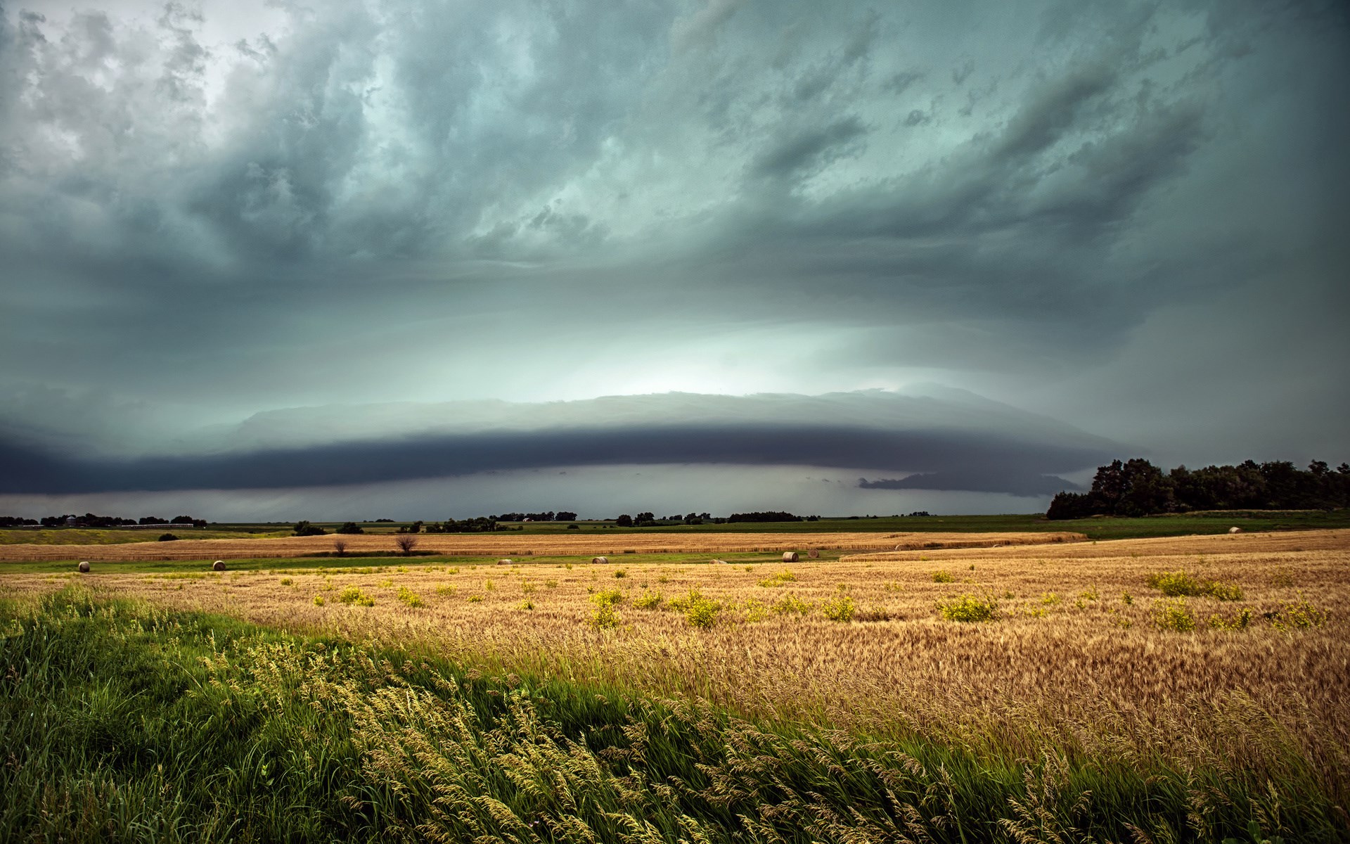 Storm clouds over a wheat field with hay bales HD Wallpaper