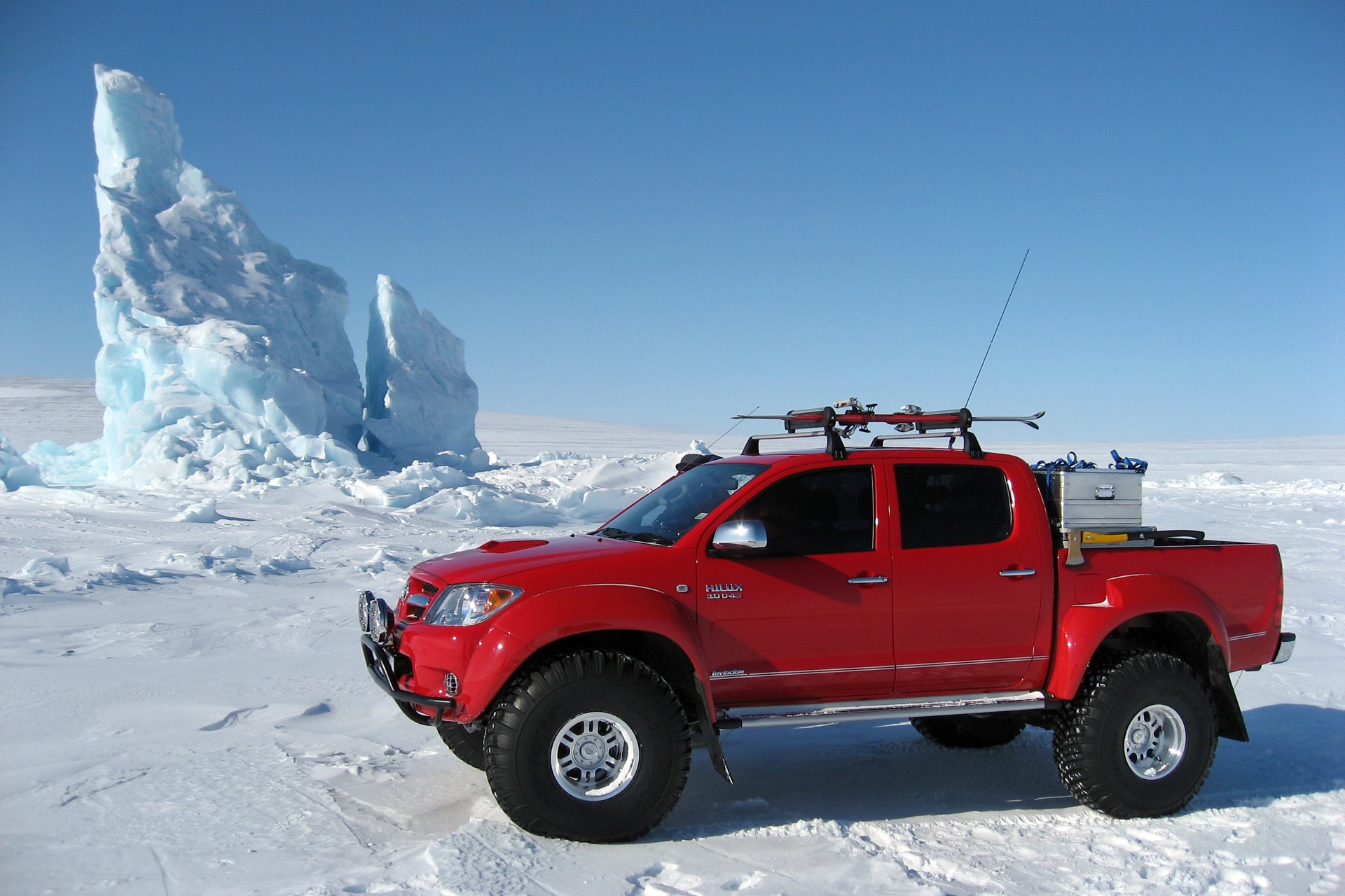 Red Toyota Hilux with skis in icy landscape HD Wallpaper