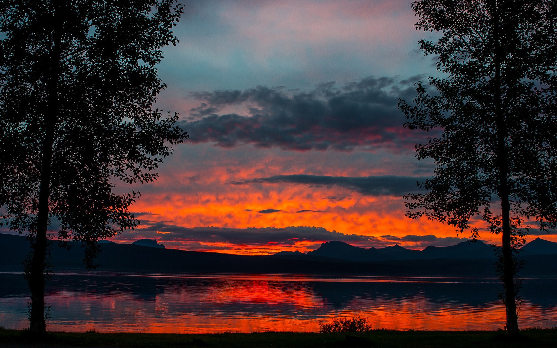 Sunset over a lake with silhouetted trees and mountains HD Wallpaper