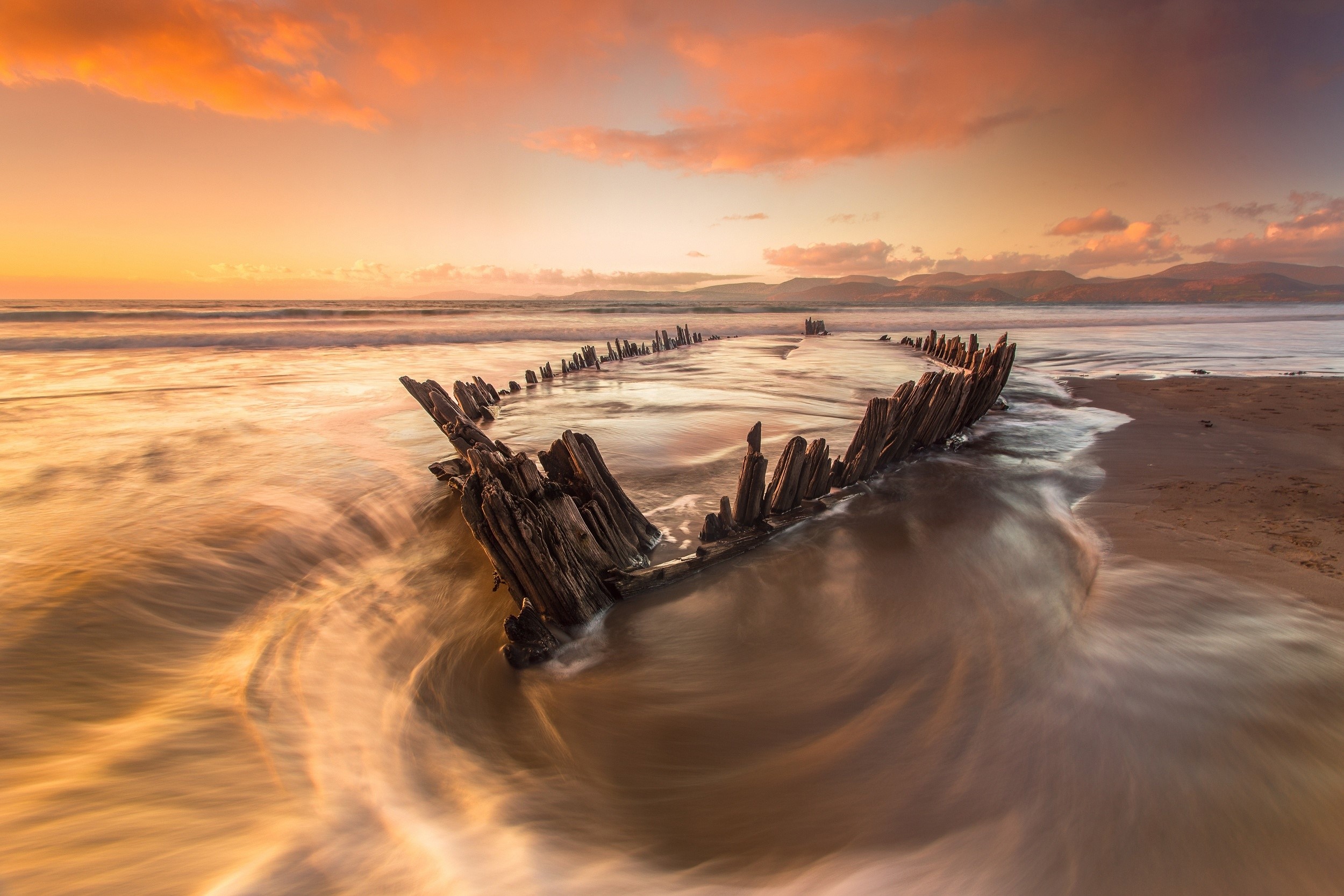 Shipwreck on a beach at sunset with waves HD Wallpaper