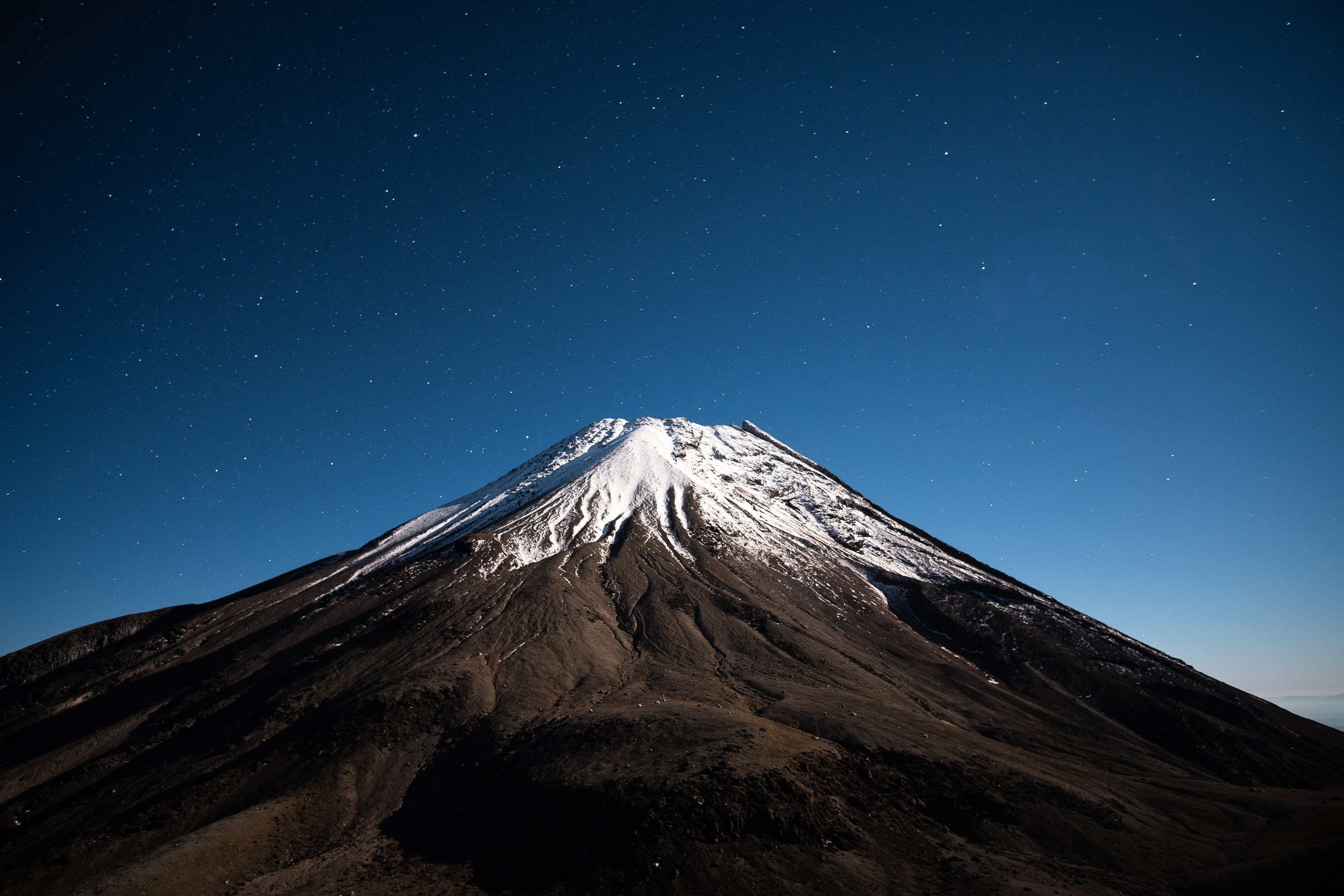 Snow-capped mountain under a starry night sky HD Wallpaper