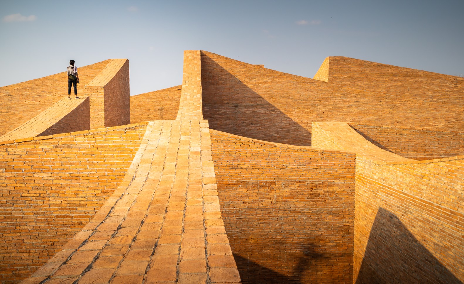 Person standing on a brick structure under a clear sky HD Wallpaper