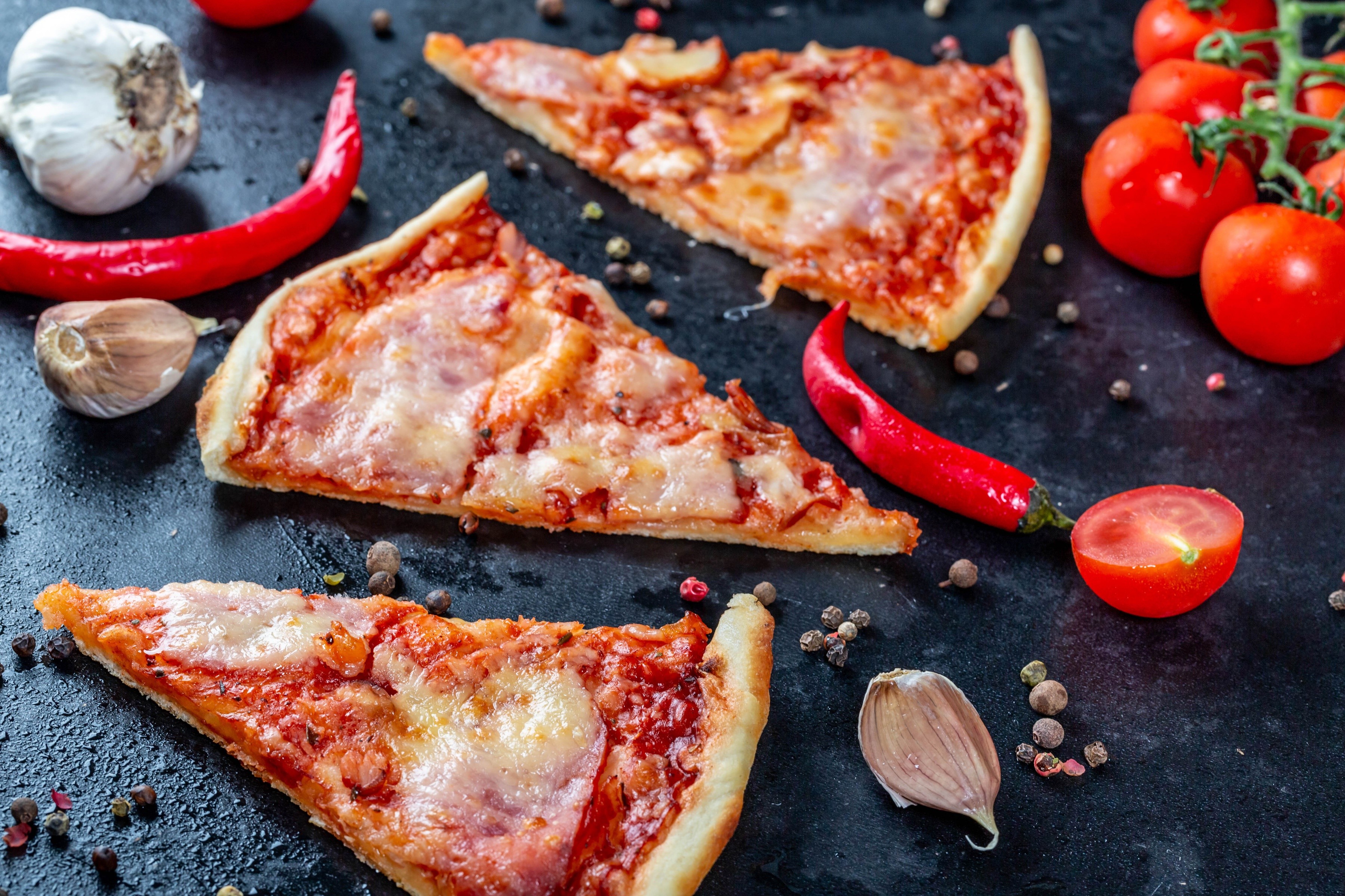 Pizza slices with tomatoes, garlic, and chili peppers HD Wallpaper