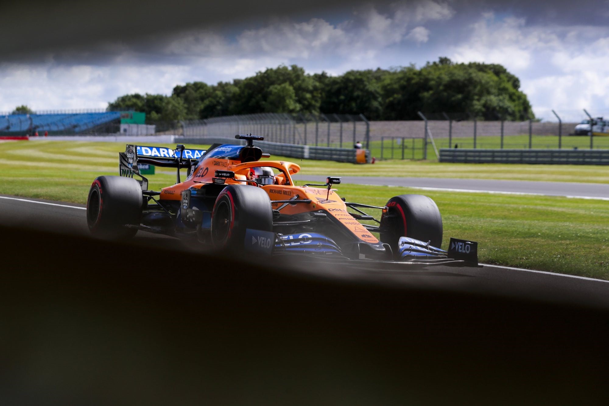 Carlos Sainz Jr. driving a McLaren F1 car on a race track HD Wallpaper