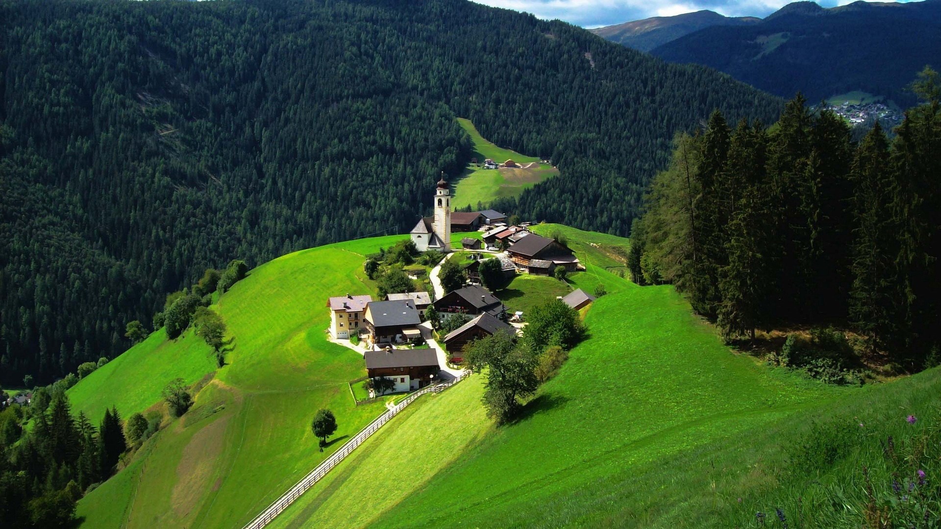 Village church on a green hillside in the Alps HD Wallpaper