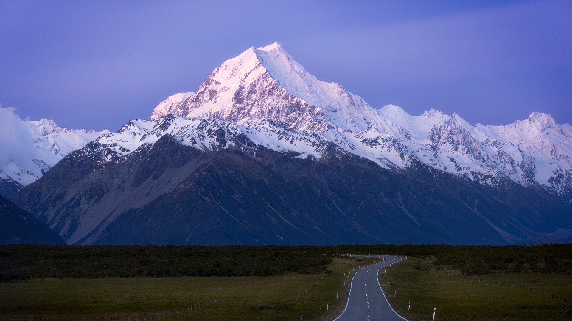 Snowy mountain range with a winding road in the foreground HD Wallpaper