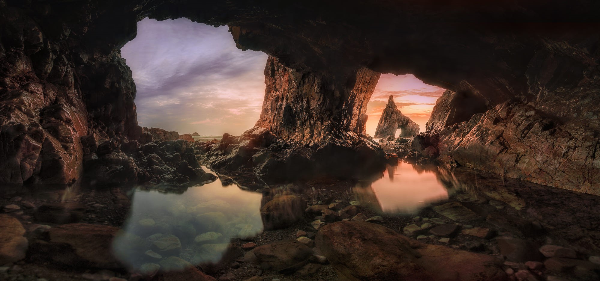 Cave entrance with rock formations and sunset reflection HD Wallpaper