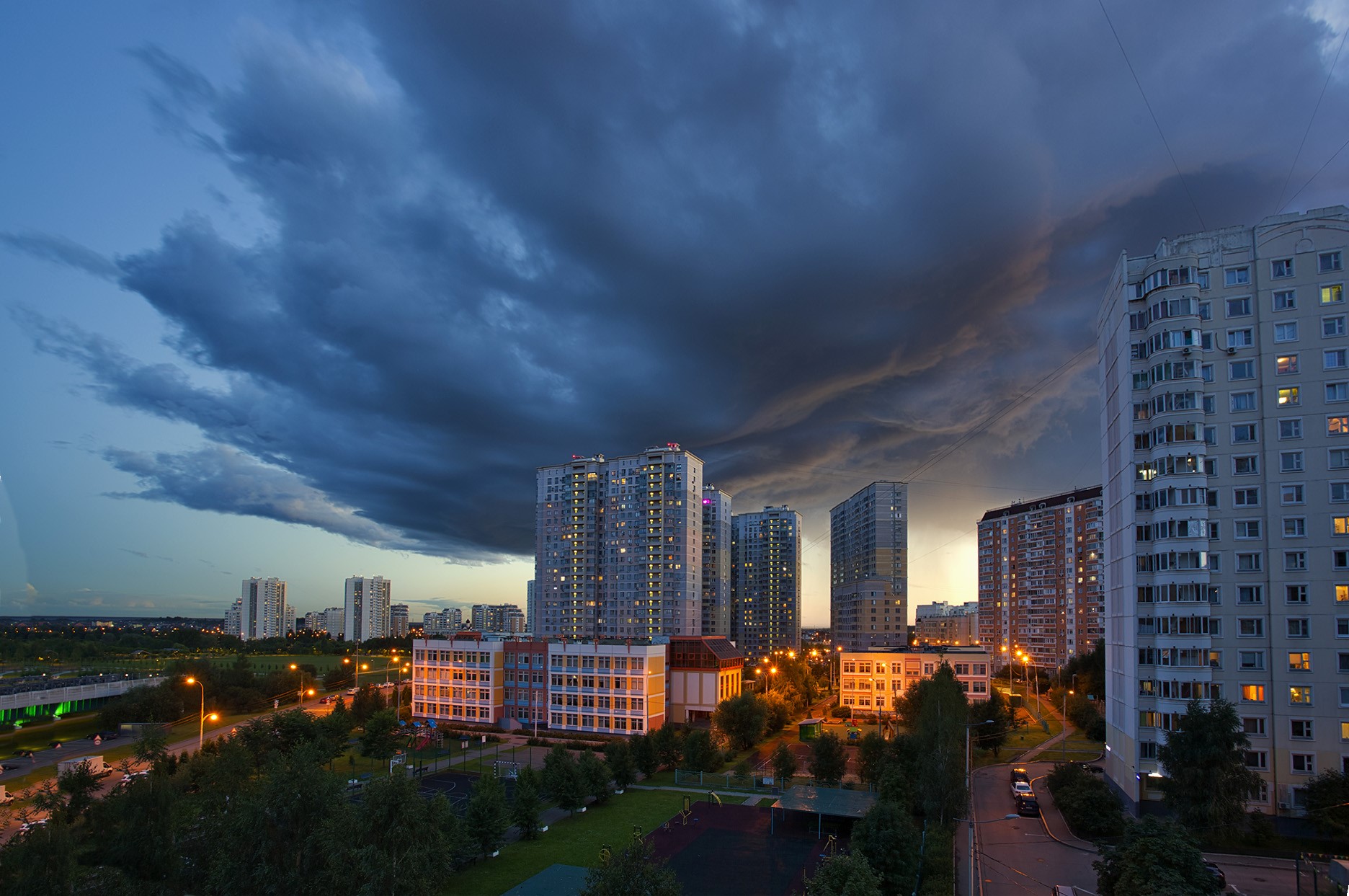 Cityscape at dusk with dramatic clouds and apartment buildings HD Wallpaper