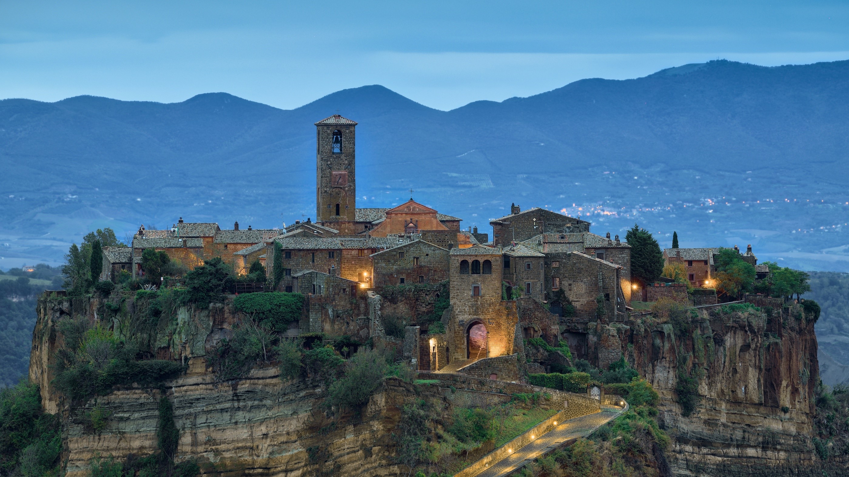 Ancient village on a cliff with mountains in the background HD Wallpaper