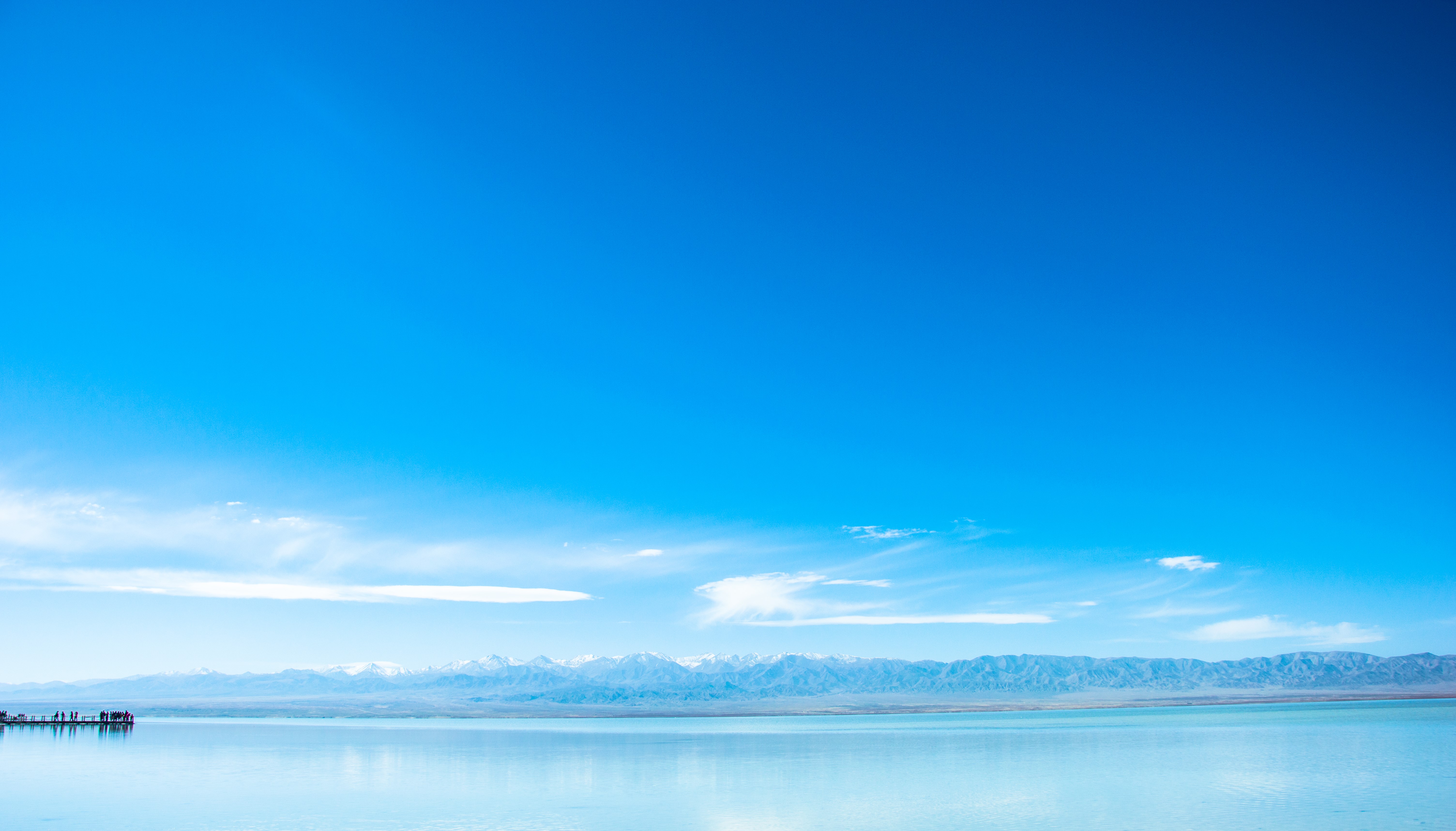 Vast blue sky over a calm lake and distant mountains HD Wallpaper