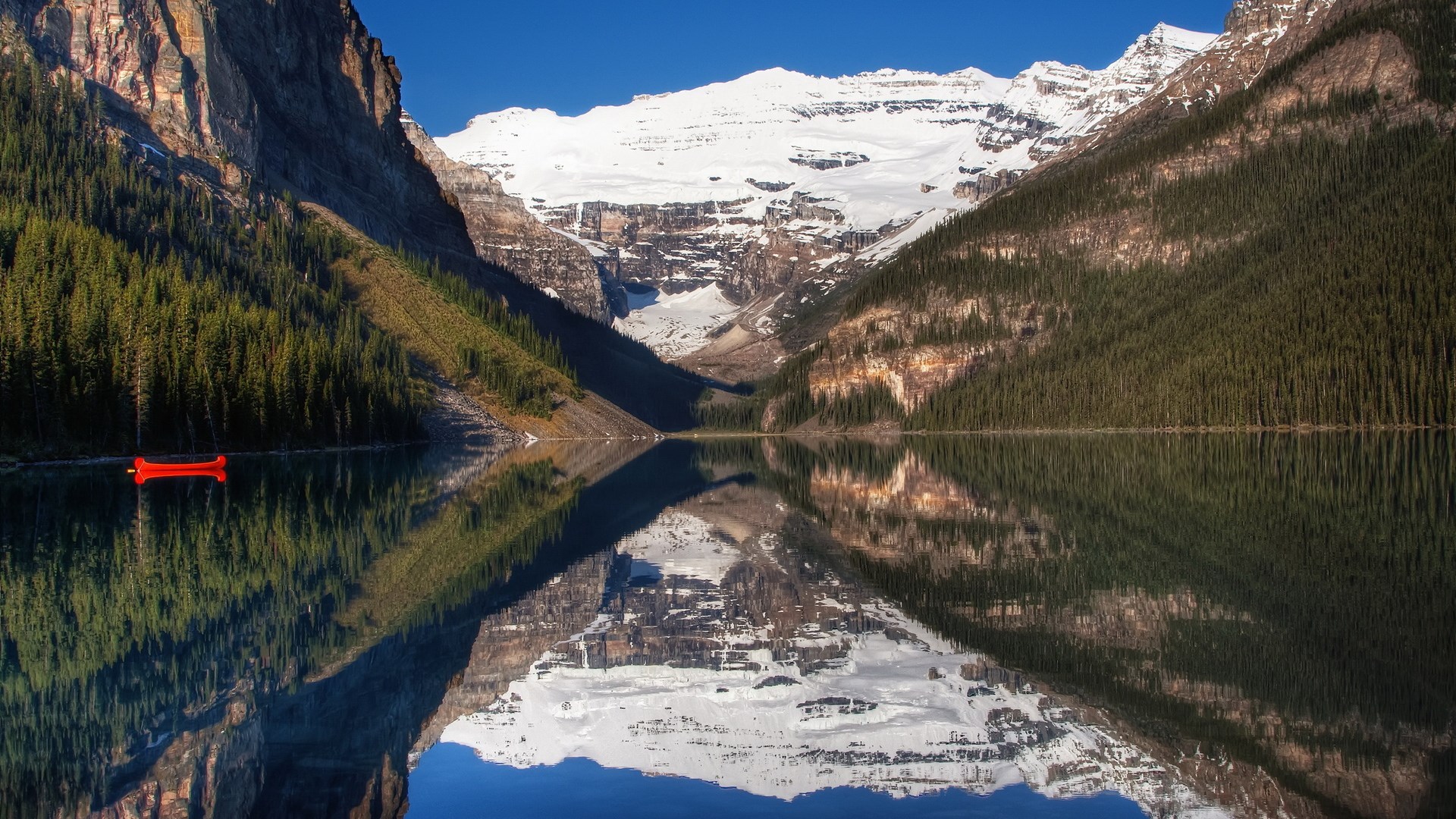 Red canoe on a calm lake with snow-capped mountains HD Wallpaper