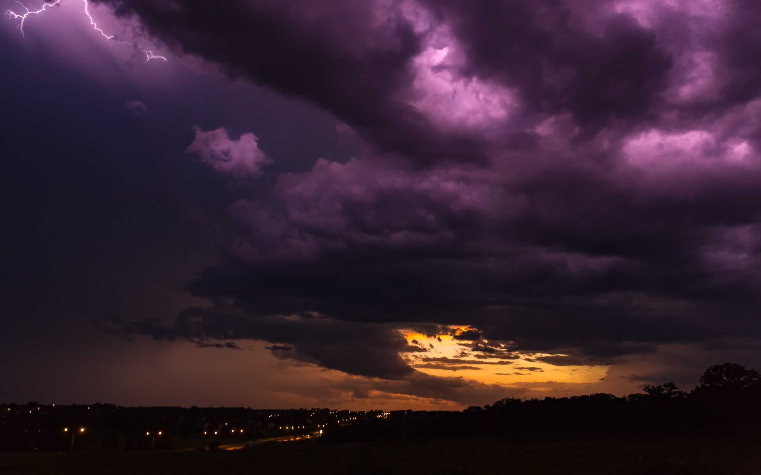Lightning strikes over a dark, stormy sky at sunset HD Wallpaper