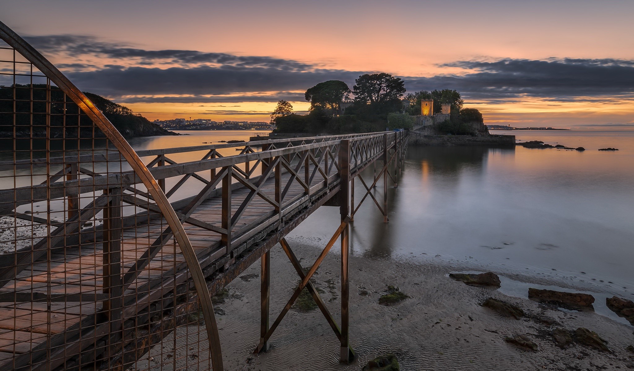 Wooden bridge leading to a castle on an island at sunset HD Wallpaper