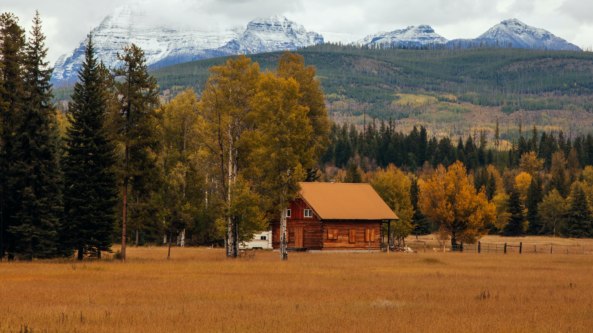 Log cabin in a meadow with snowy mountains HD Wallpaper