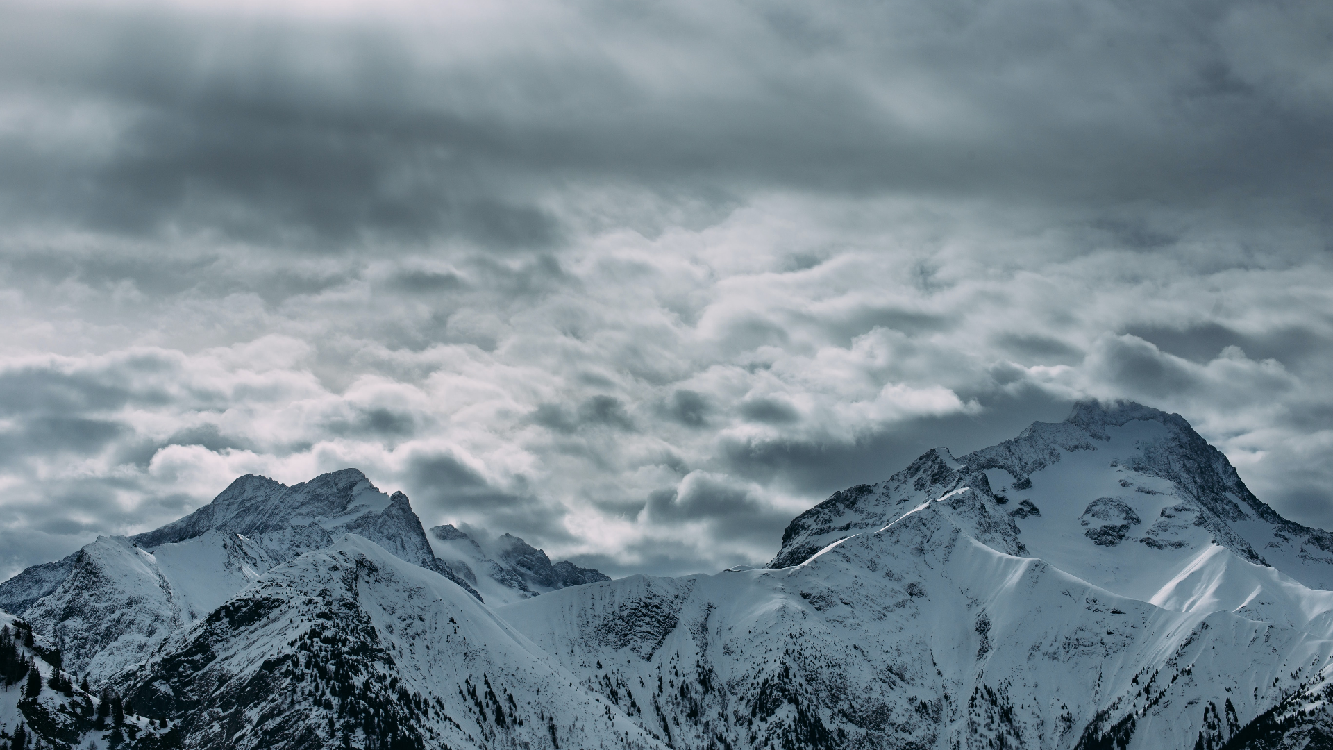 Snowy mountains under a cloudy sky HD Wallpaper