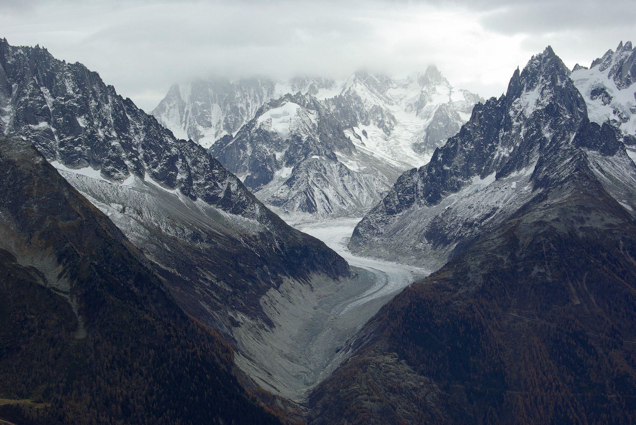 Snow-capped mountains and a glacier under a cloudy sky HD Wallpaper