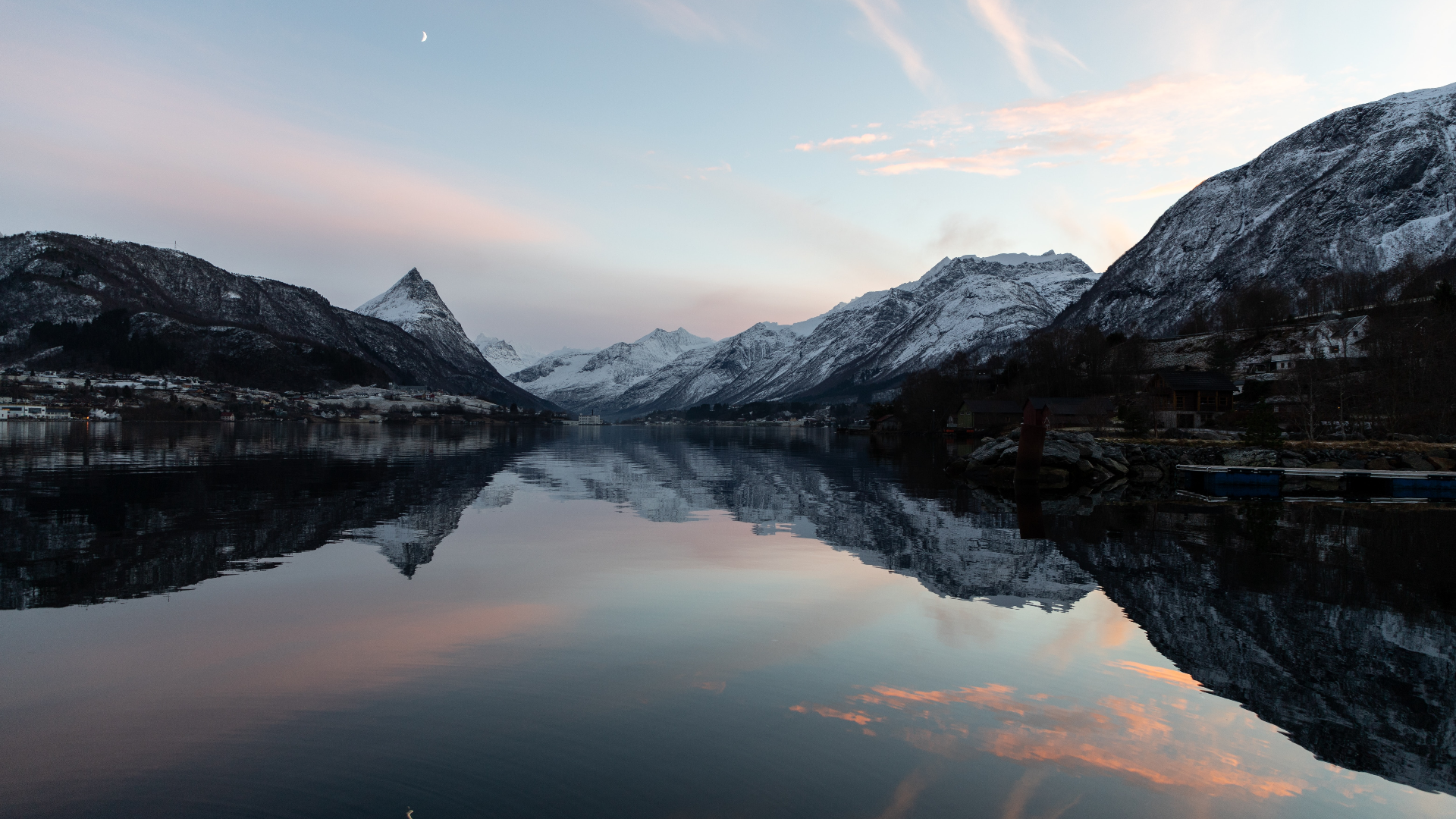 Snow-capped mountains reflected in a fjord under a pastel sky with a crescent moon HD Wallpaper