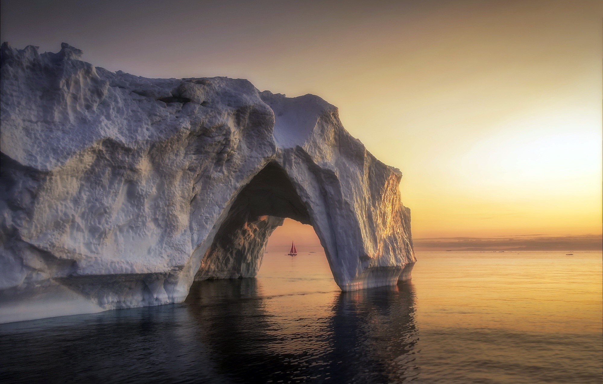 Iceberg arch with sailboat at sunset HD Wallpaper