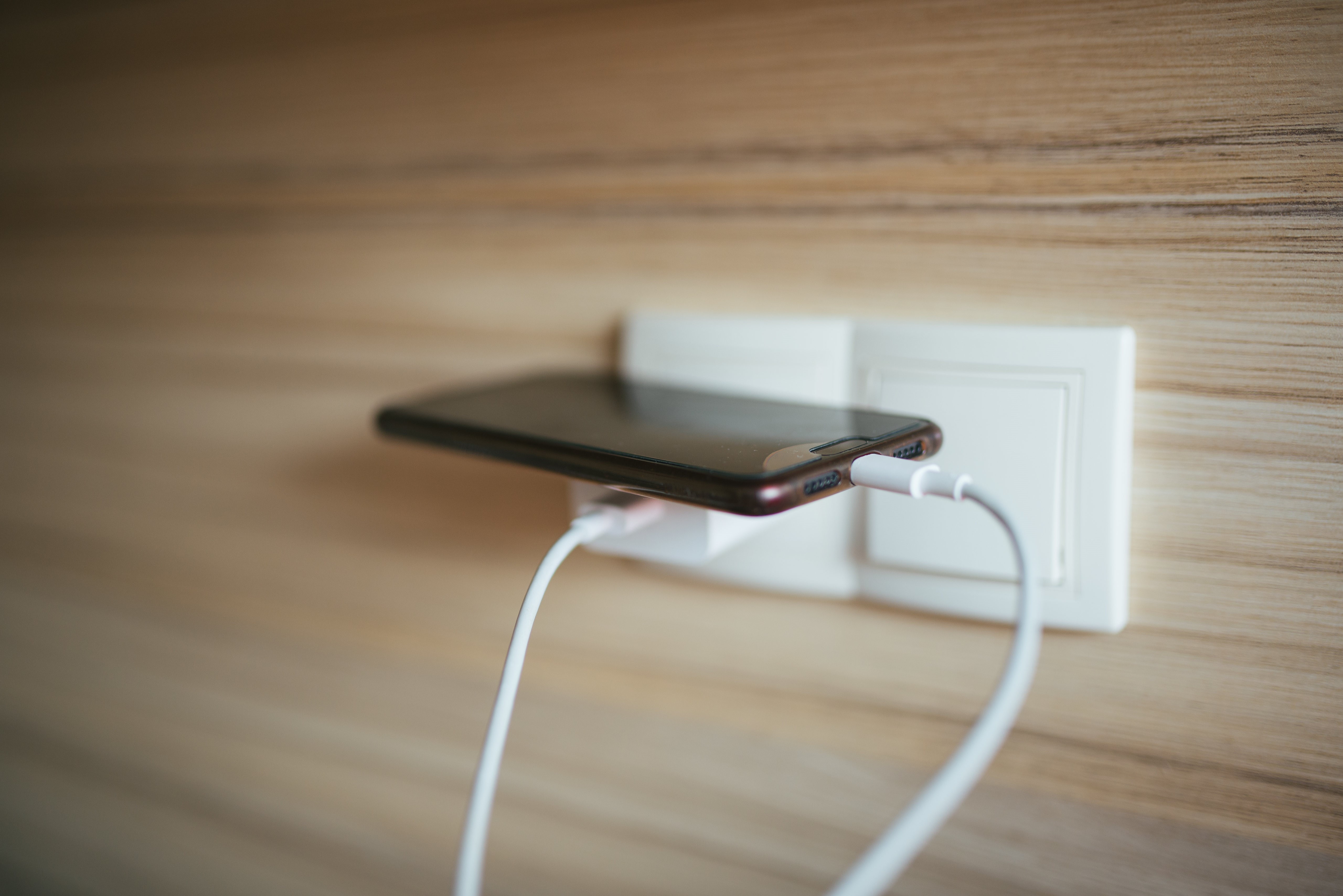 Smartphone charging in wall outlet HD Wallpaper