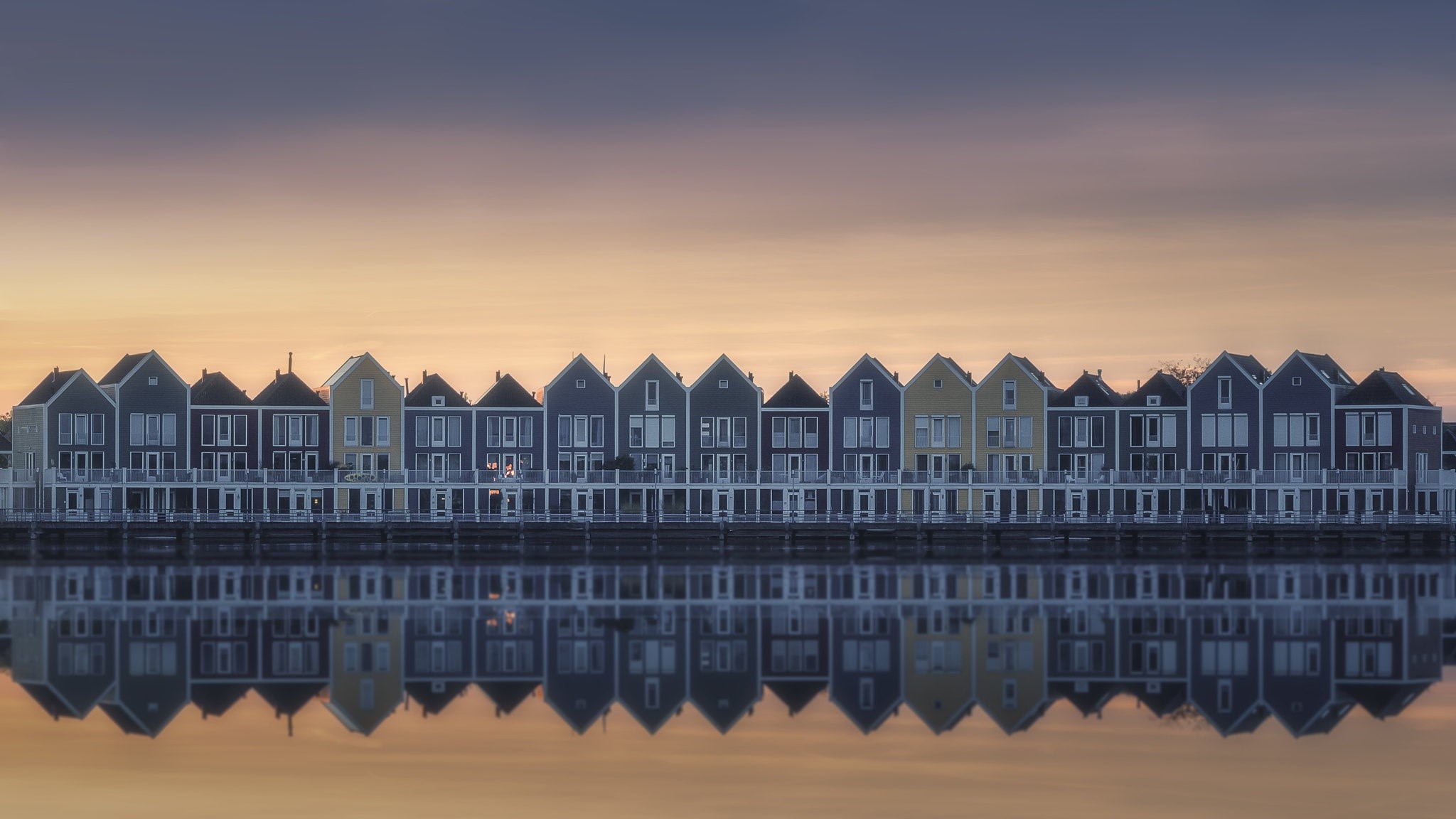 Row of colorful houses reflected in water at sunset HD Wallpaper