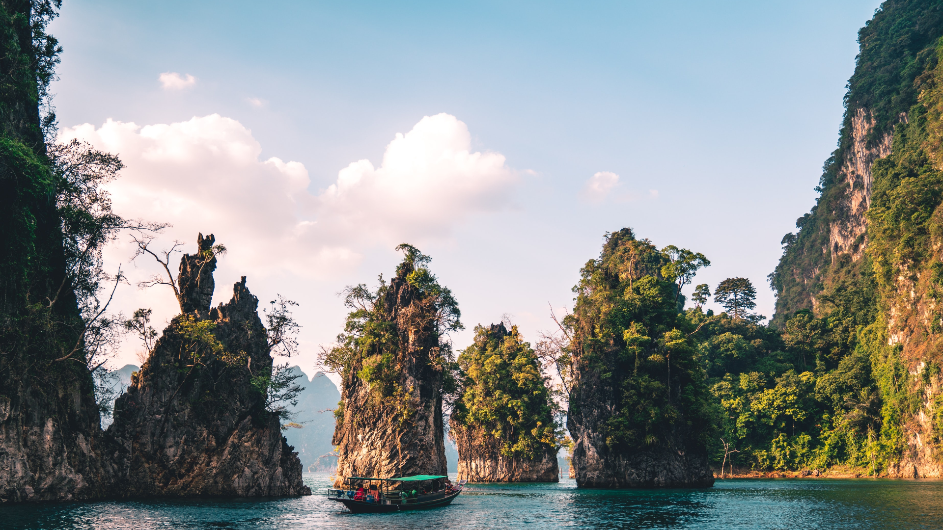 Boat navigating through limestone karsts in Thailand HD Wallpaper