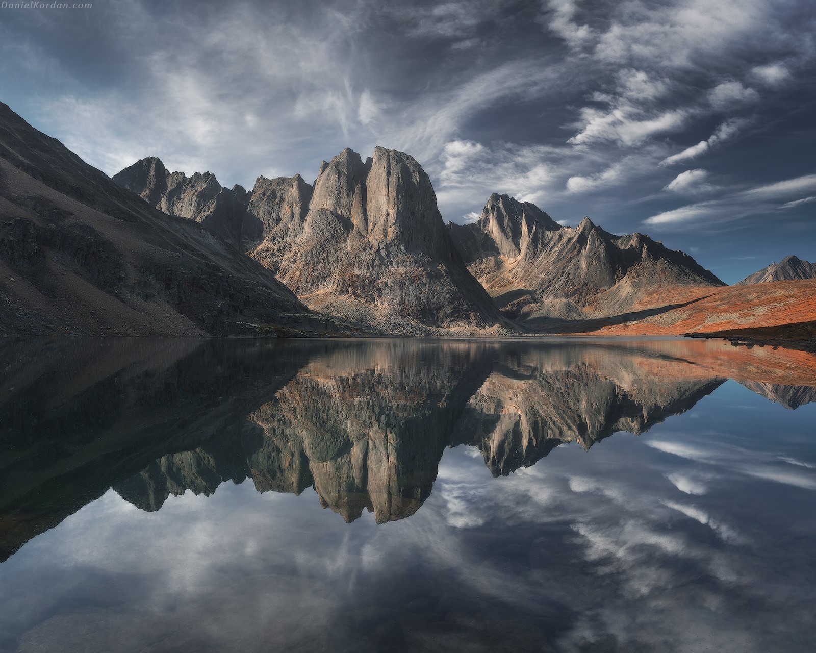 Mountains reflected in a lake under a cloudy sky HD Wallpaper