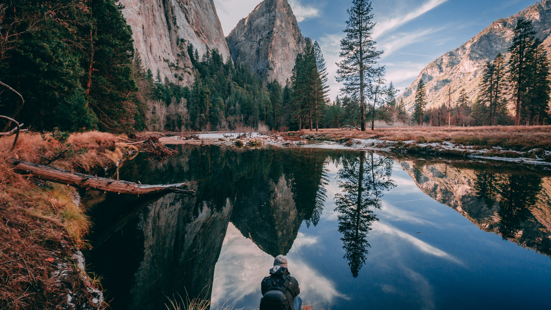 Man sitting by a reflective lake in Yosemite National Park HD Wallpaper