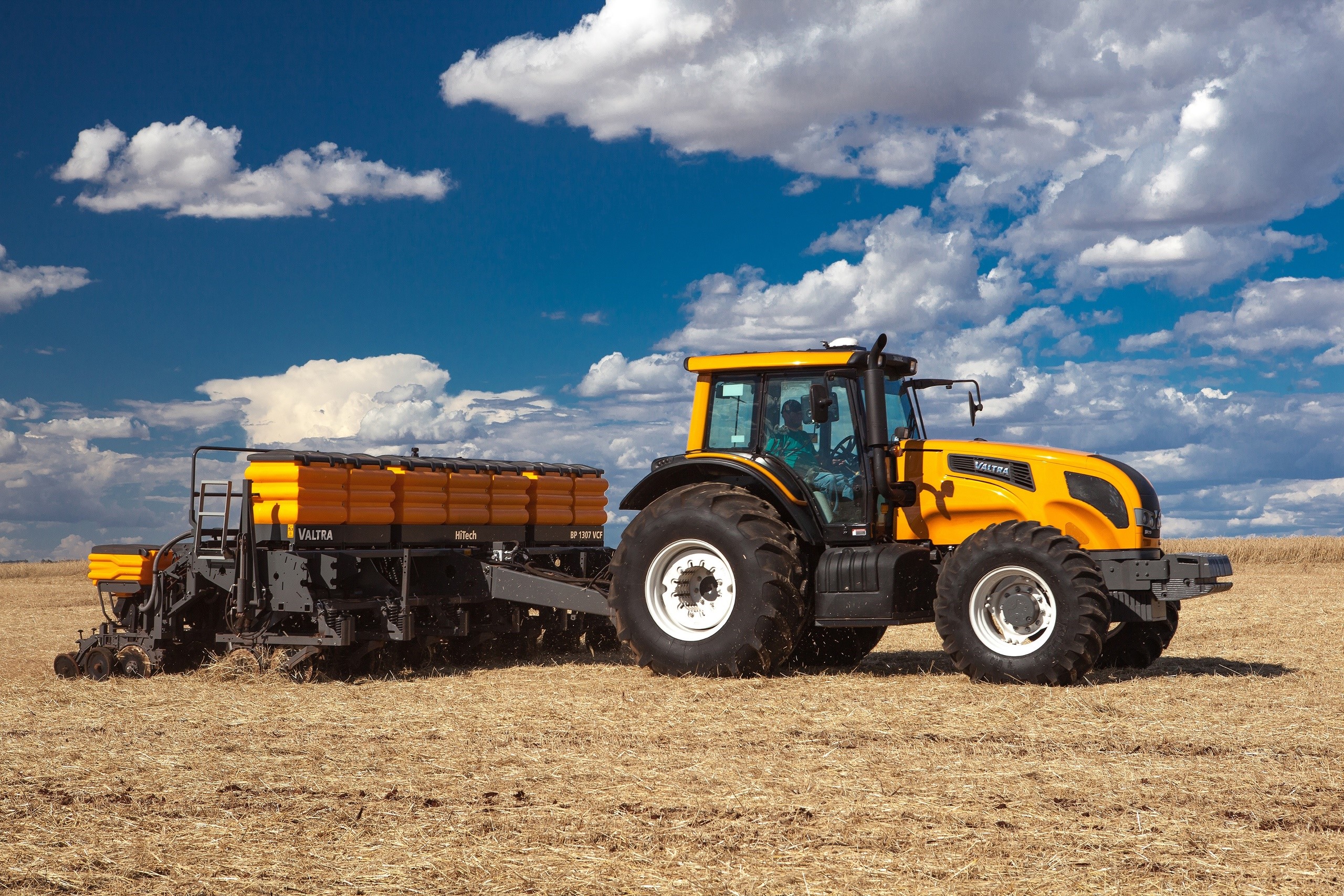 Yellow Valtra tractor pulling a planter in a dry field HD Wallpaper