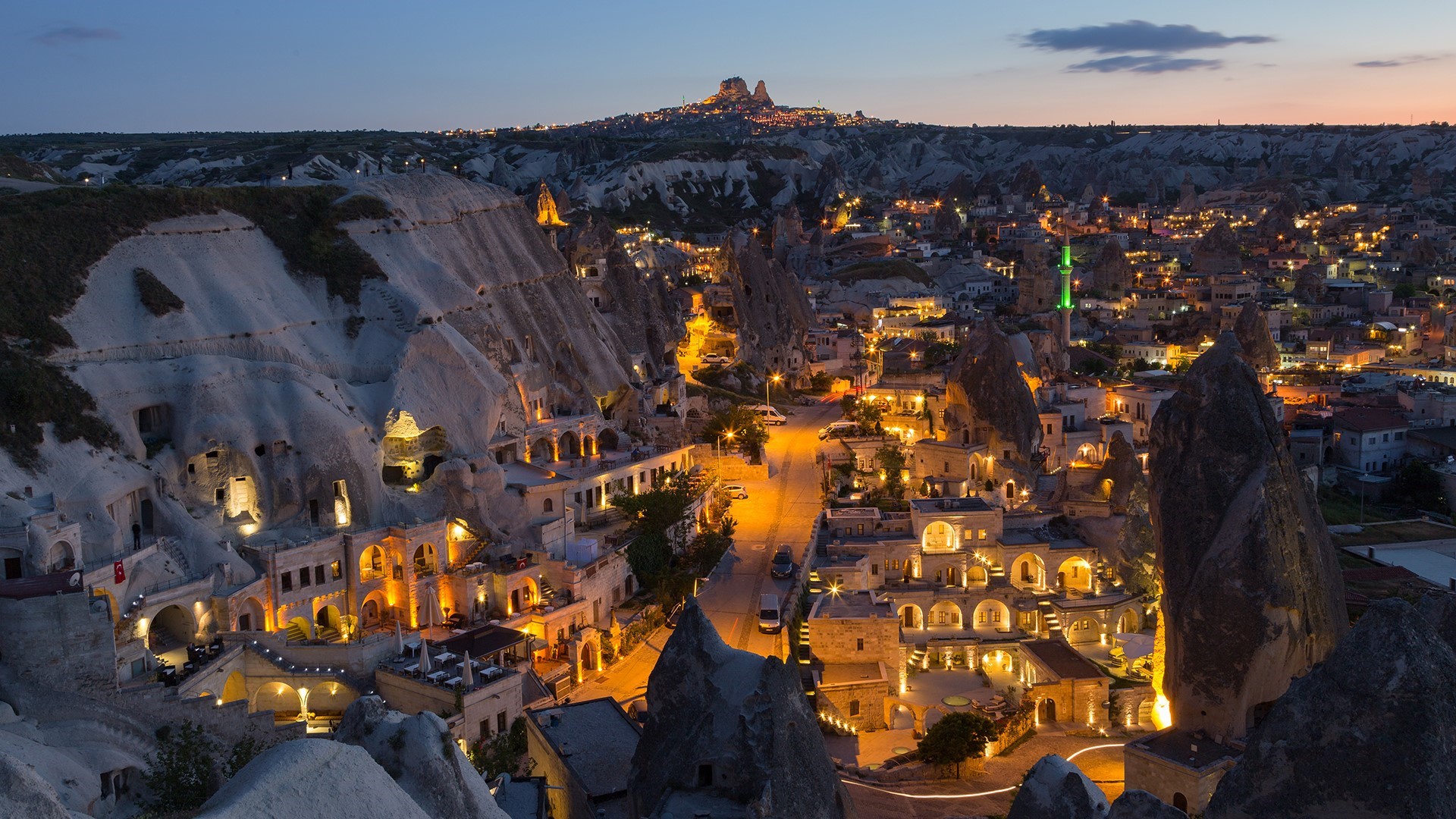 Cave dwellings and town lights in Cappadocia, Turkey at dusk HD Wallpaper